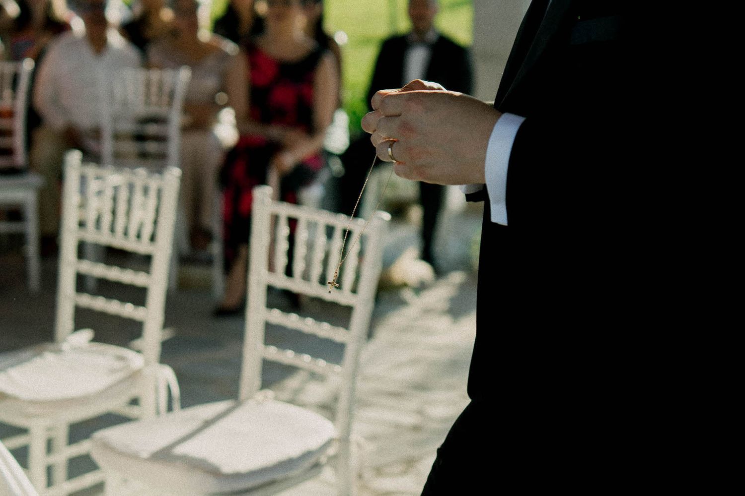 Close-up shot of formal attire and white chairs at an outdoor wedding ceremony.