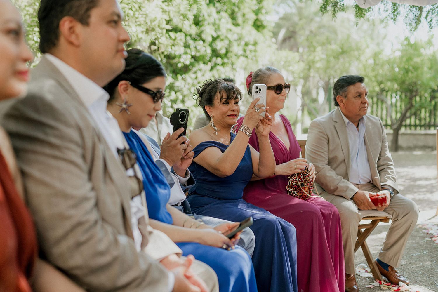 Wedding guests enjoy drinks and conversation during an outdoor garden reception.