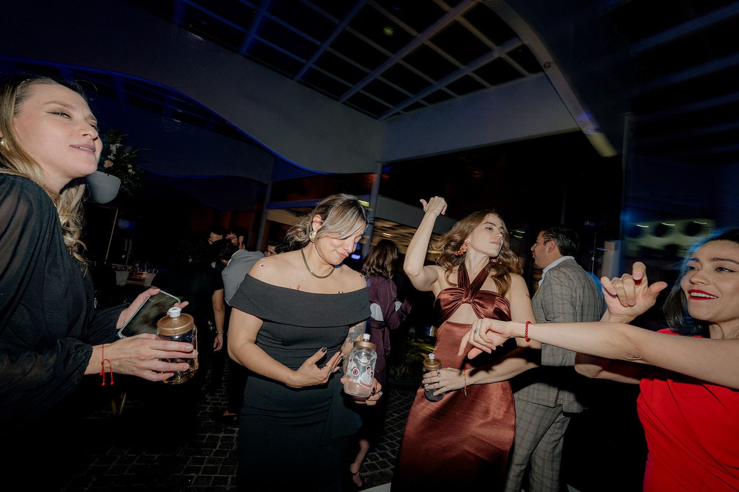 Guests dancing and celebrating joyfully at a lively indoor wedding reception party.