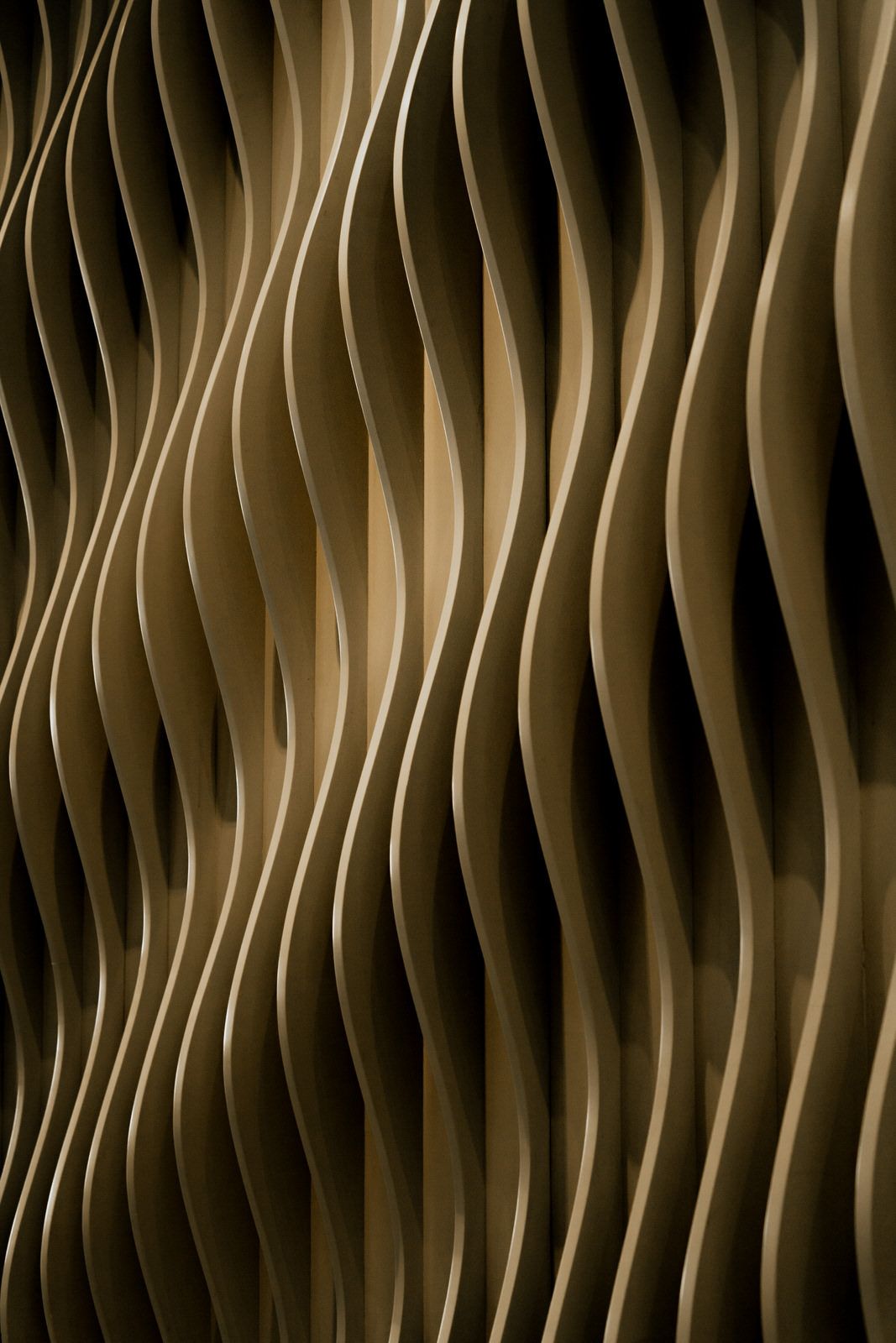 Abstract golden wavy textured wall panel with flowing vertical curves.