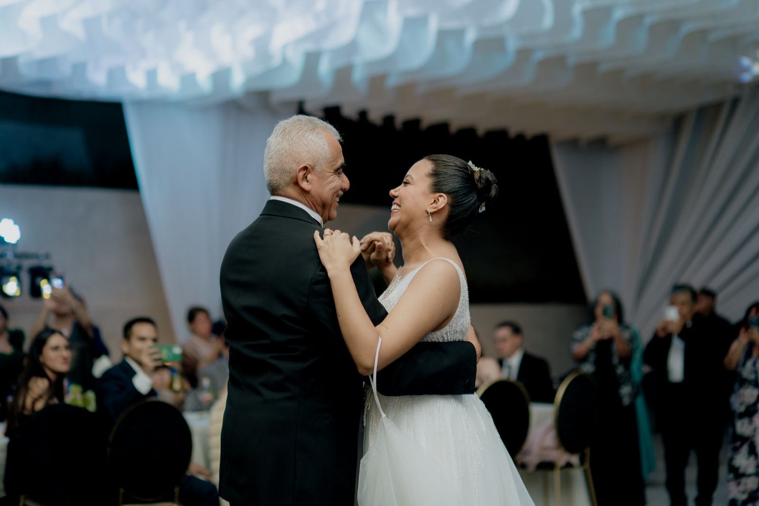 Bride and groom share an intimate first dance at elegant wedding reception with guests watching.
