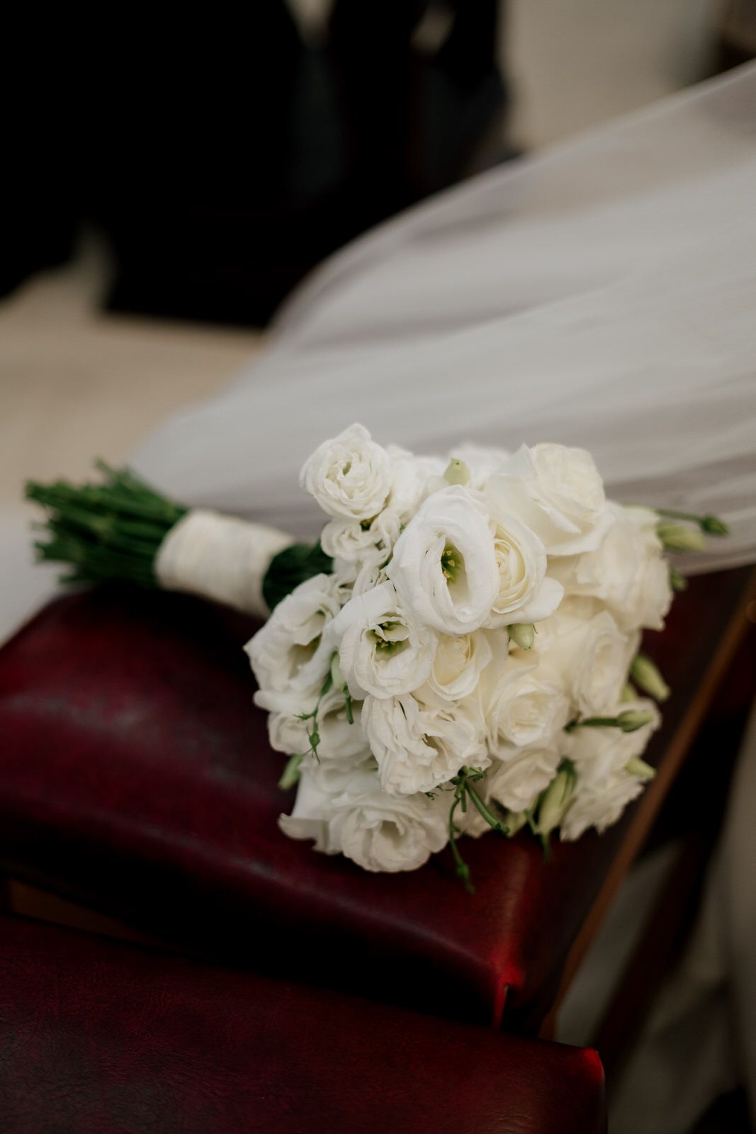 White roses and floral decorations adorn church pews at a wedding ceremony.