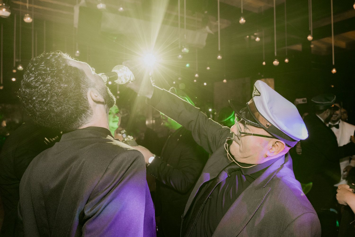 Purple and gold lighting creates a dramatic atmosphere at an indoor wedding reception.