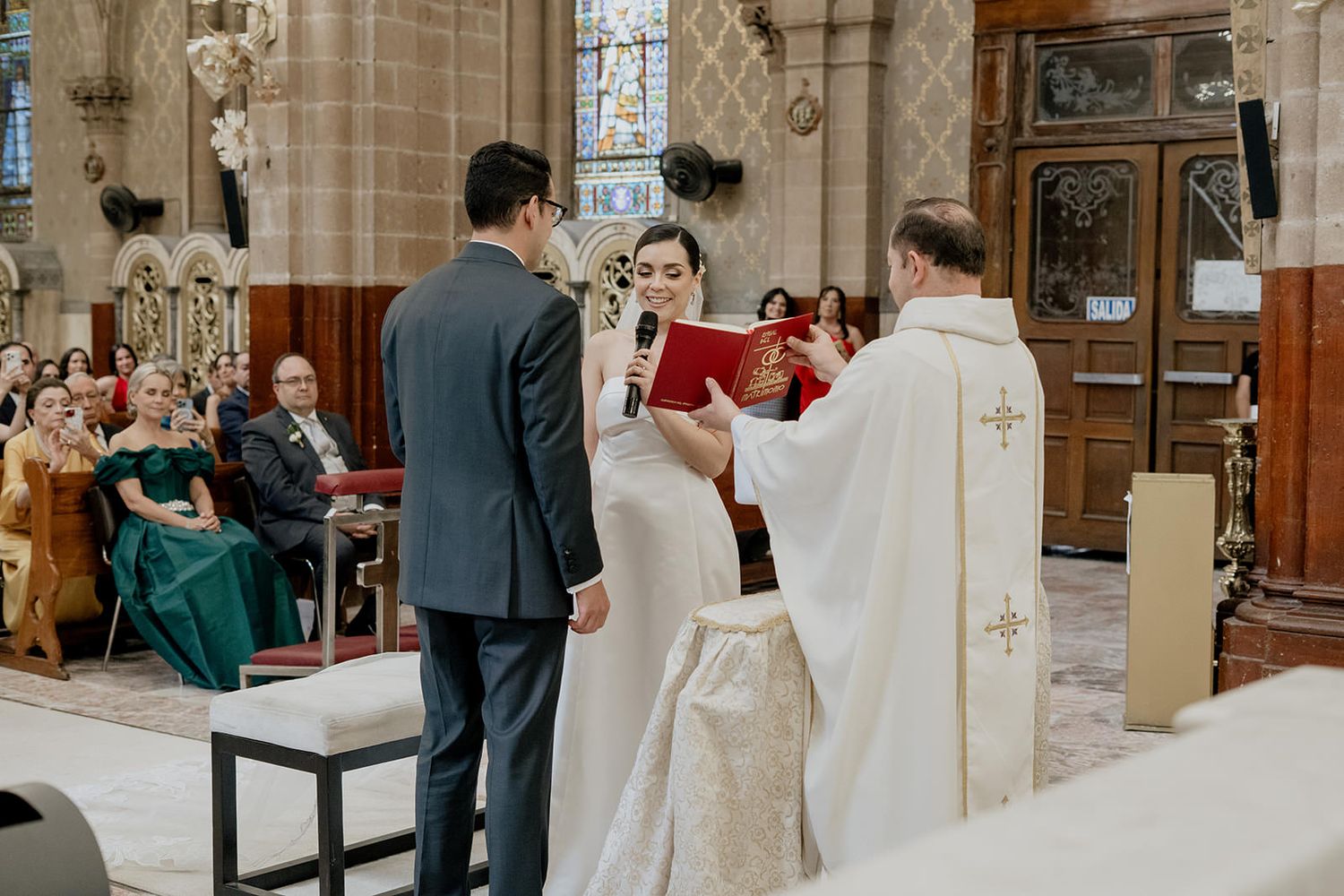 Bride and groom exchanging vows at a traditional church wedding ceremony with priest officiating.