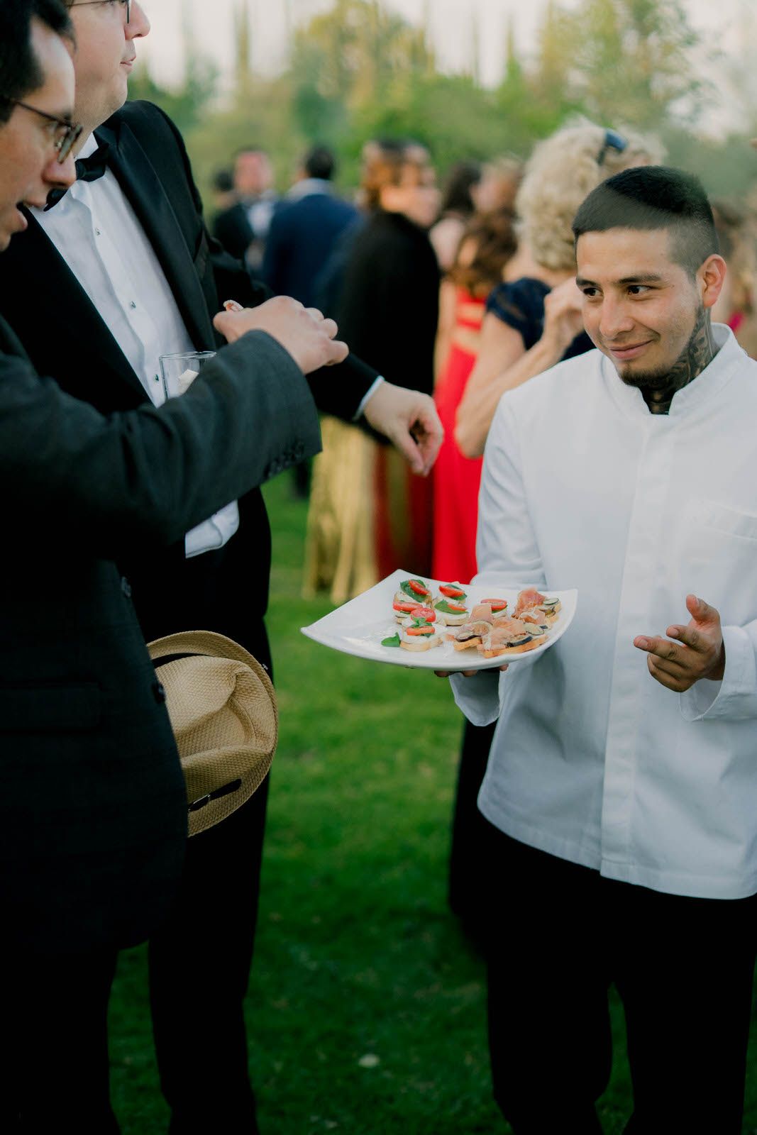 Wedding catering staff serving appetizers to guests at outdoor reception.