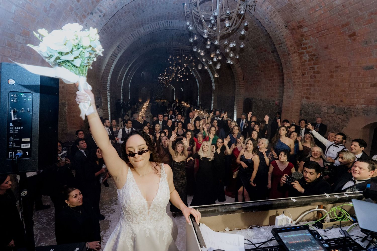 A celebration in a brick-walled venue with a crowd of dancing party guests.