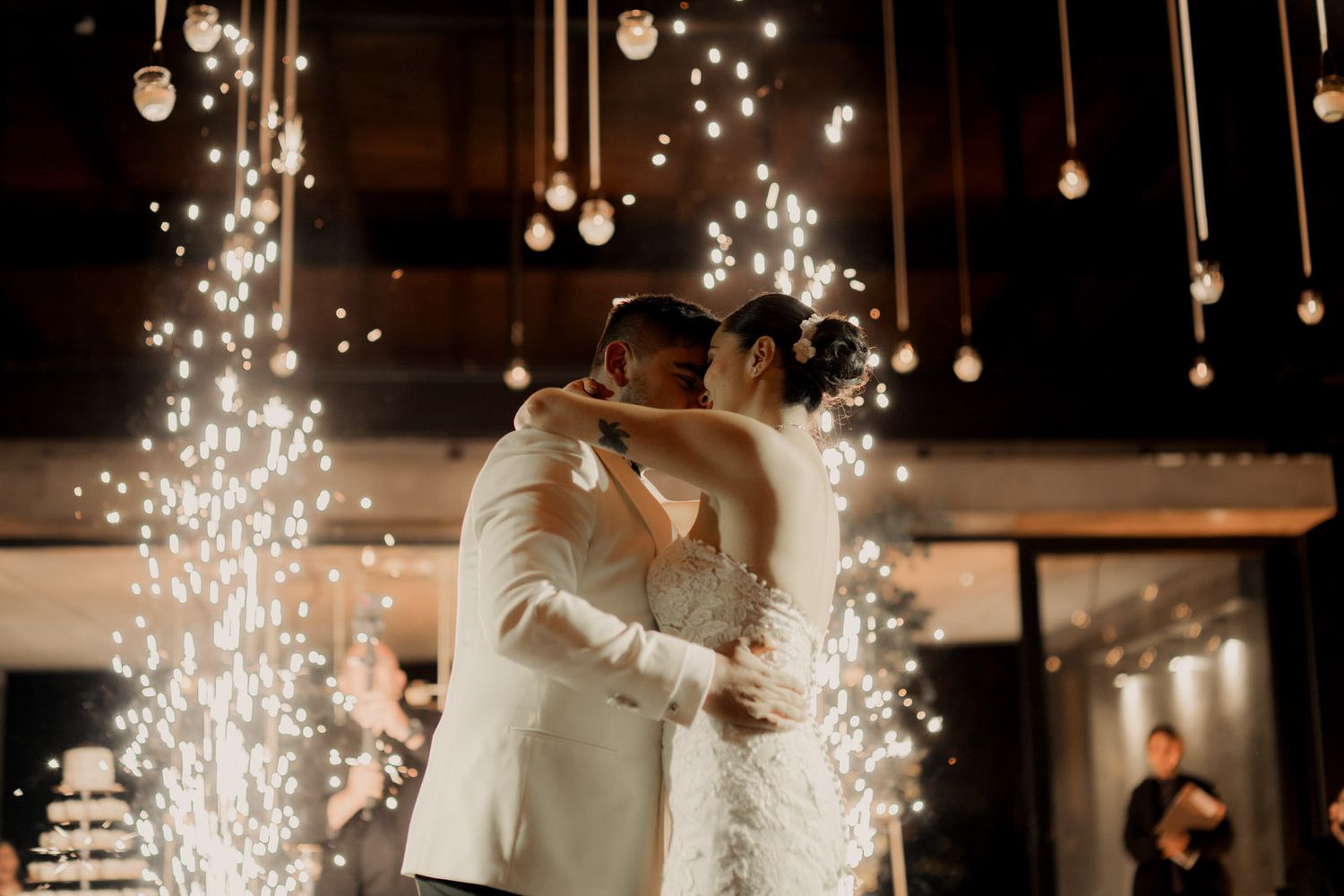 Sparklers illuminate a wedding dance floor as guests celebrate under suspended string lights.