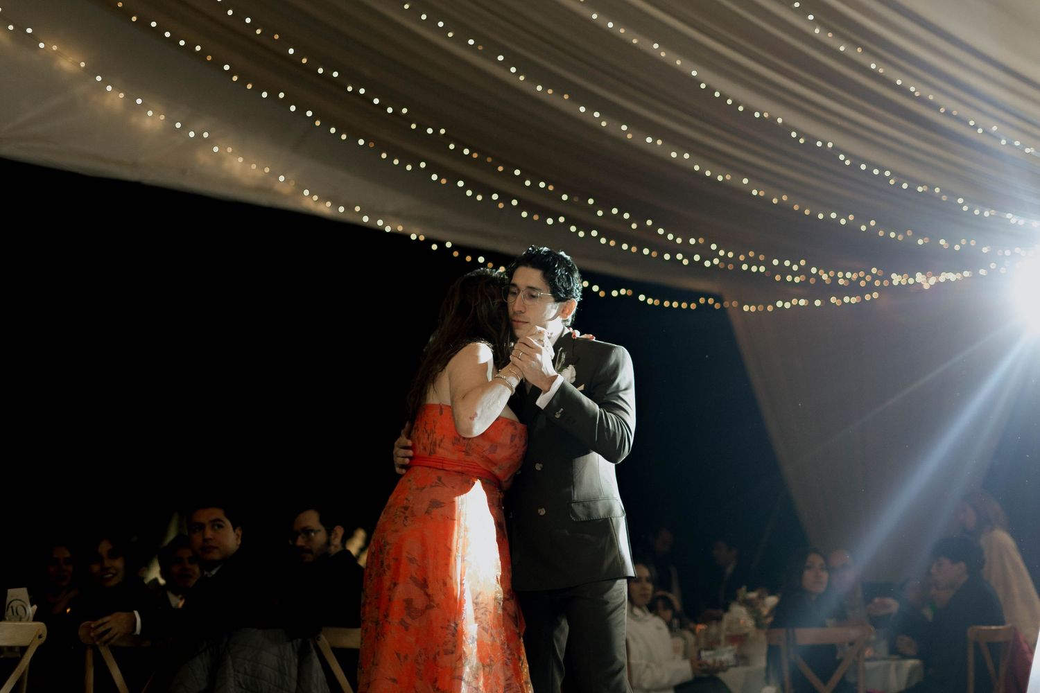 Wedding reception under string lights with smoke effects creating a dreamy atmosphere.