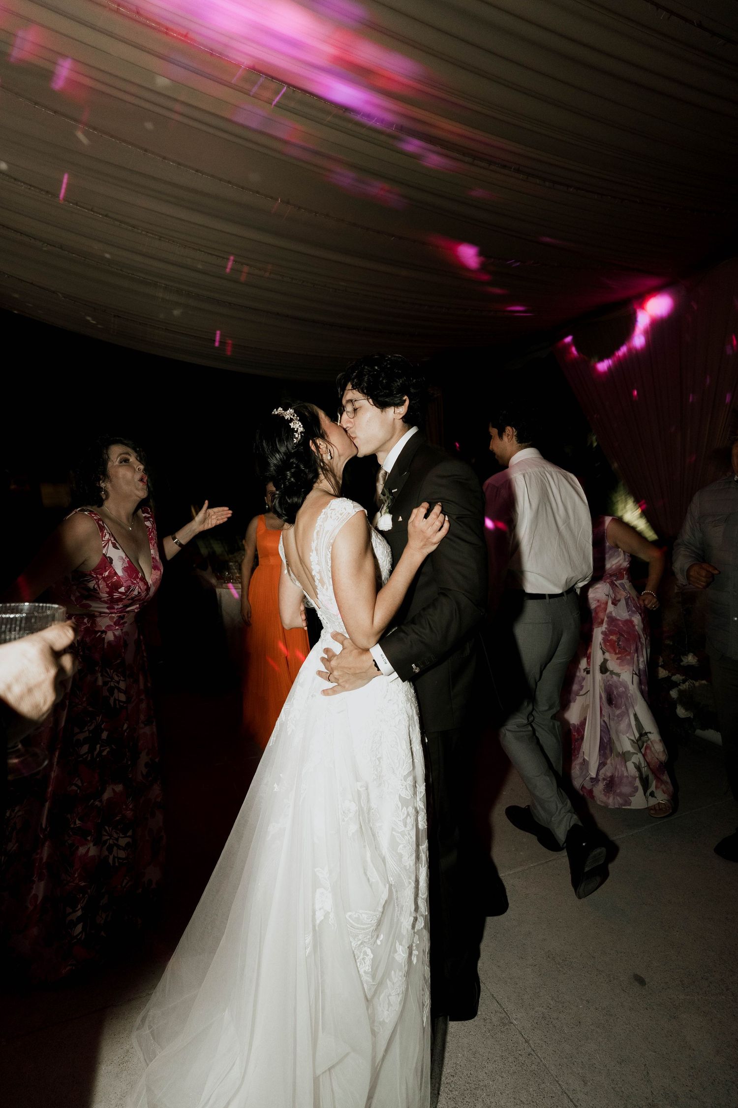 Couple dancing together under pink and purple lighting at their wedding reception.