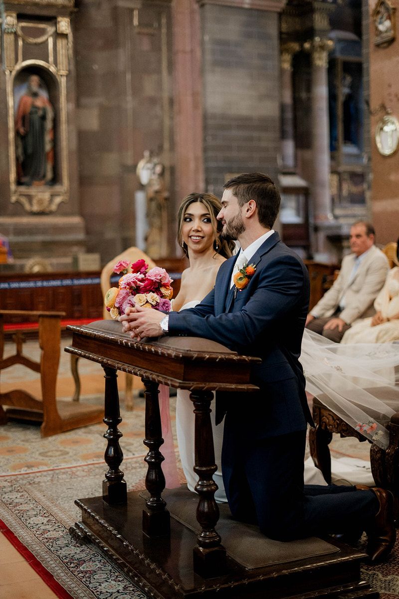 A wedding ceremony moment in a historic church with ornate wooden details and floral arrangements.