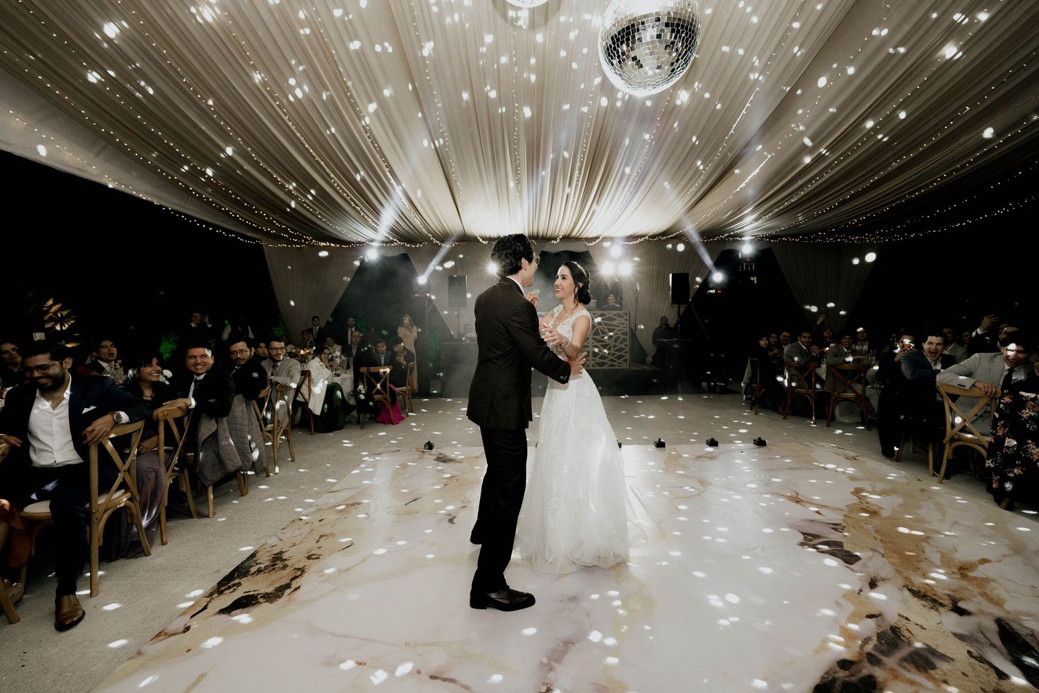 Panoramic view of a wedding reception space with dramatic lighting and ceiling decorations.