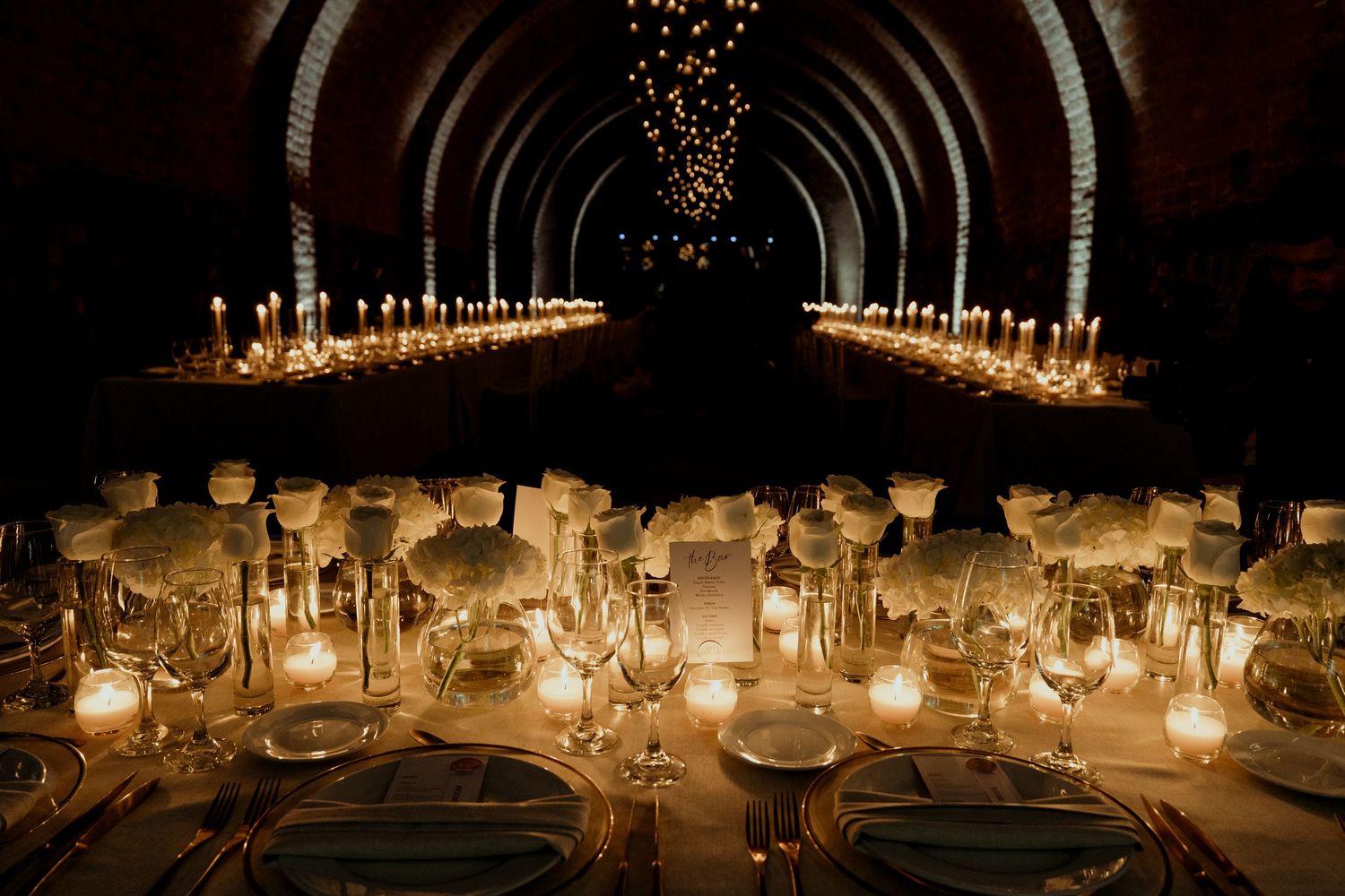 Romantic candlelit table settings with glowing centerpieces in an intimate dining space.