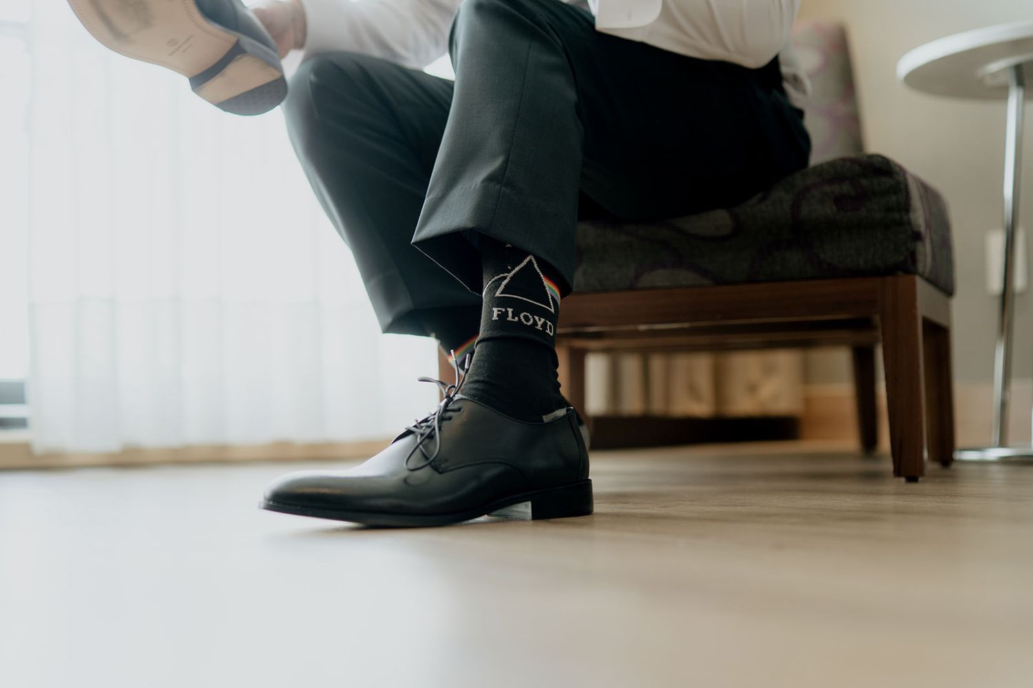 Groom wearing fun patterned socks and black dress shoes while getting ready for his wedding.