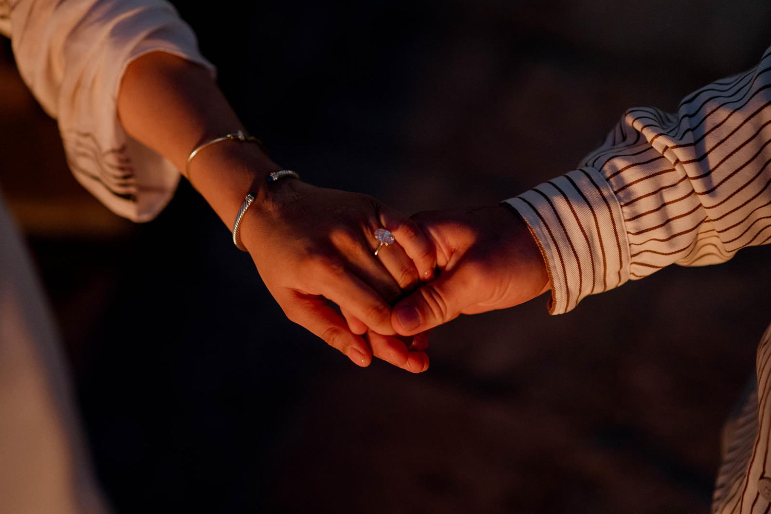 Hands clasped together in an emotional moment during sunset.