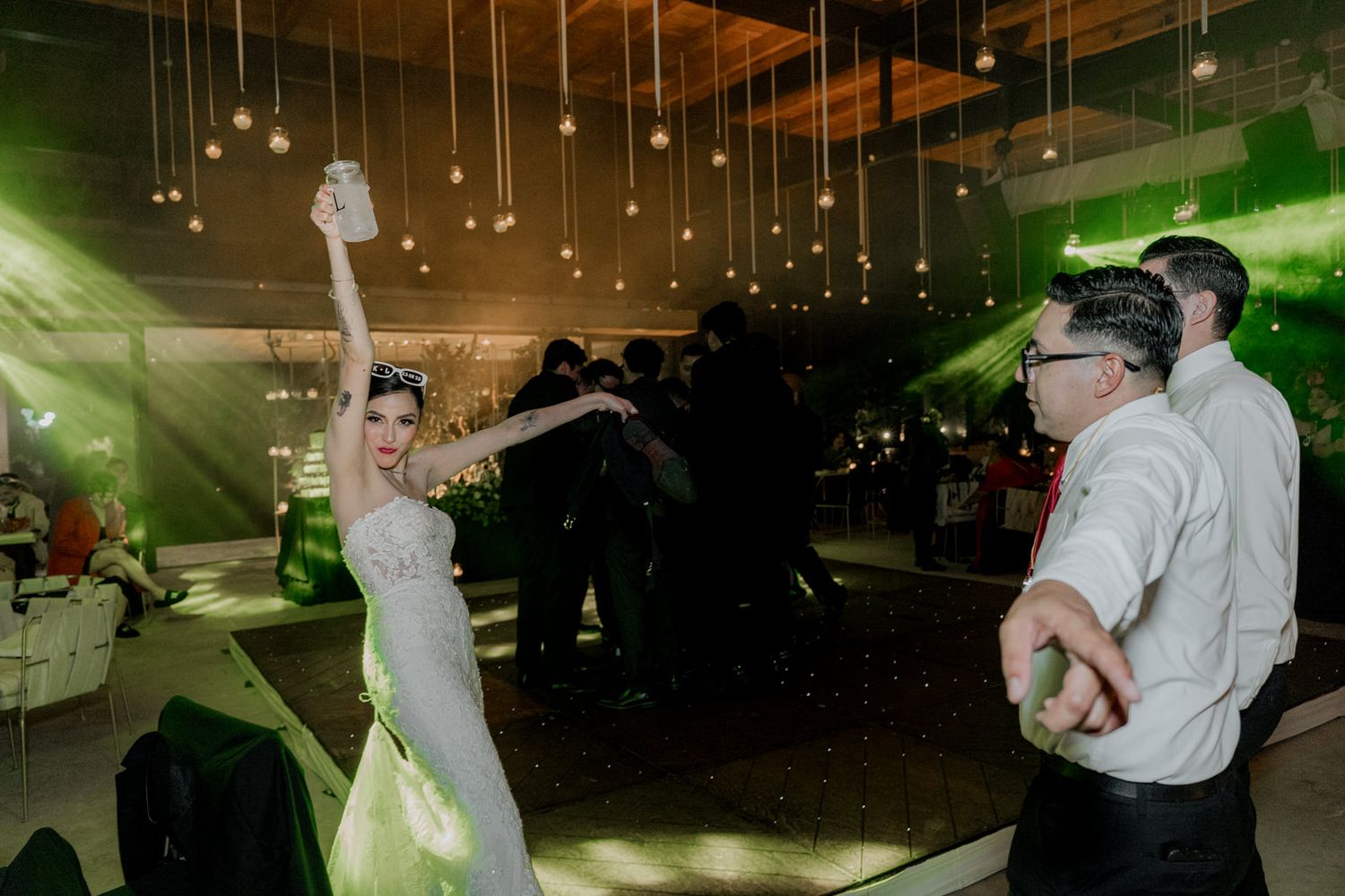 Dance floor filled with wedding guests under warm lighting and exposed wooden beams.