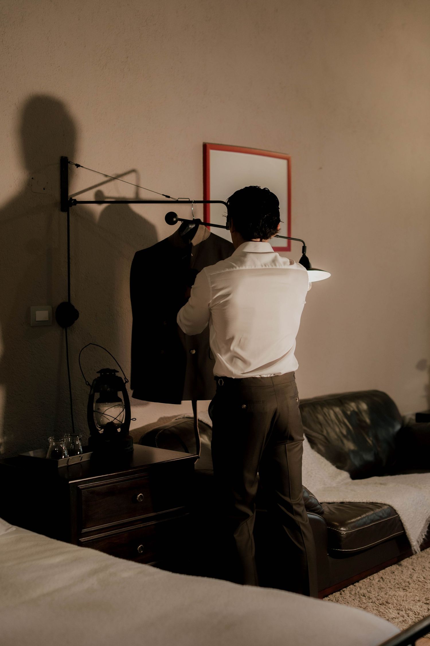 Moody interior shots of a dimly lit bedroom with silhouetted figures preparing for a formal event.