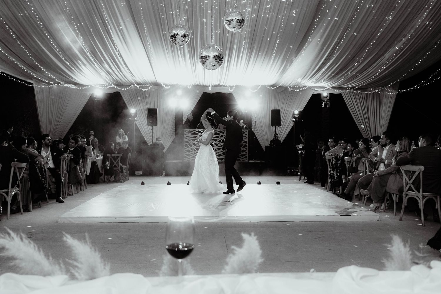 Wide-angle shot of a wedding reception dance floor with dramatic lighting and ceiling decor.
