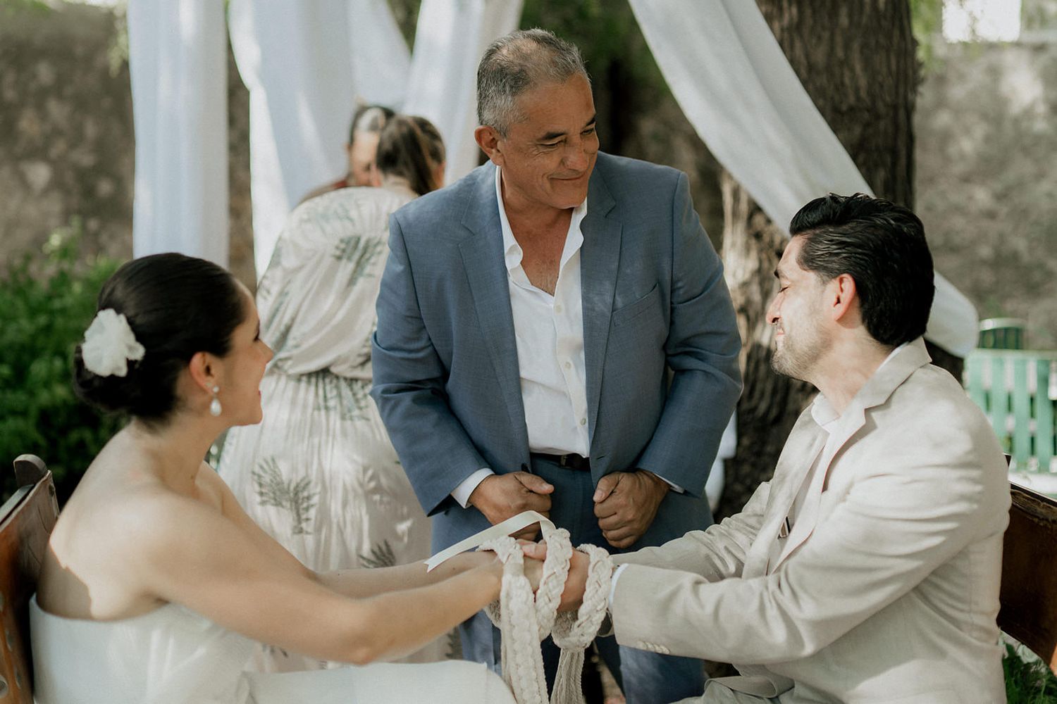 Wedding celebration in a garden setting with decorative white fabric and natural stone elements.