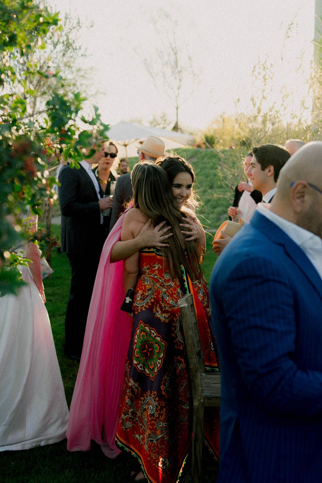Wedding guests mingling outdoors during sunset celebration.