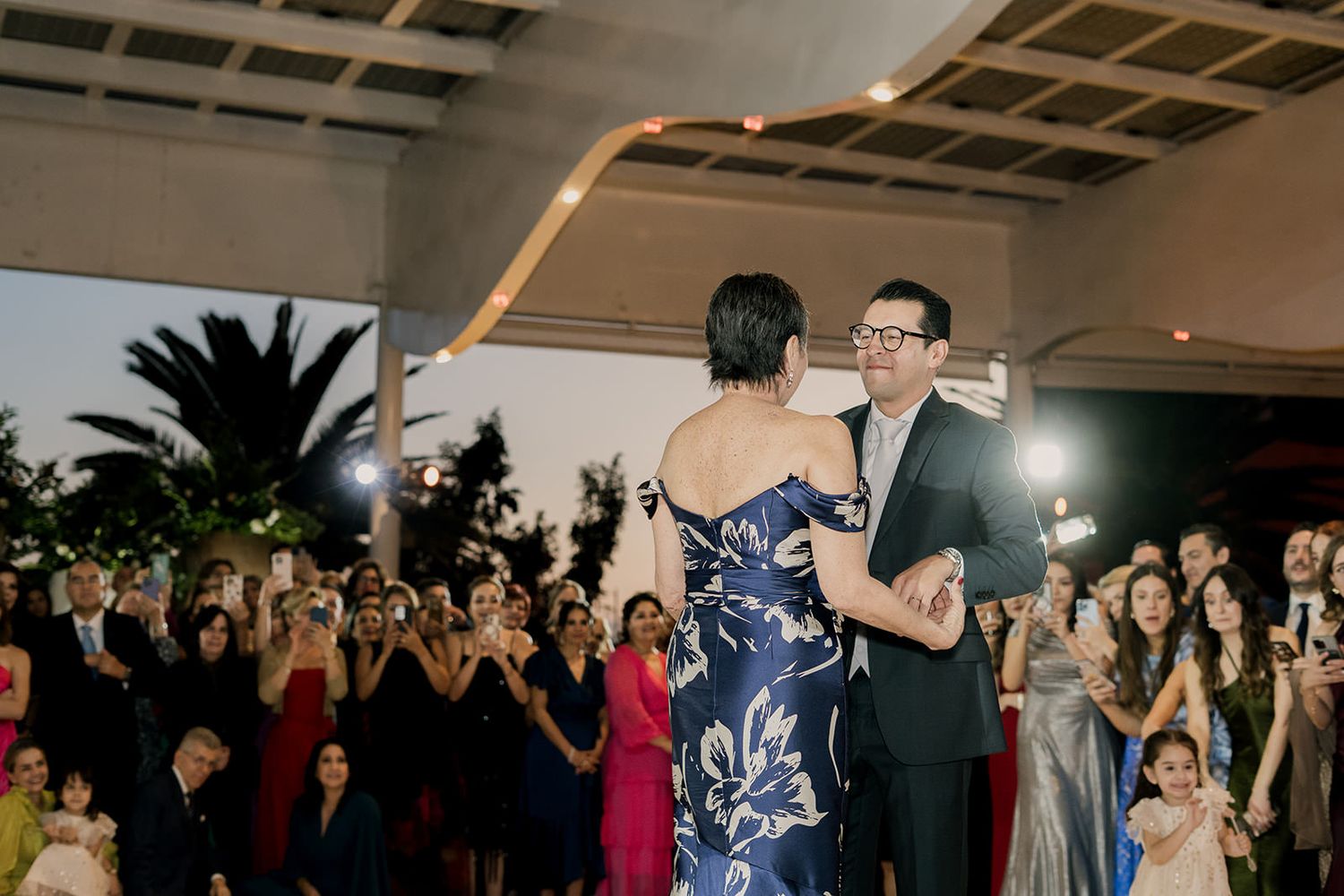 Couple shares a romantic first dance at an elegant outdoor evening wedding reception.