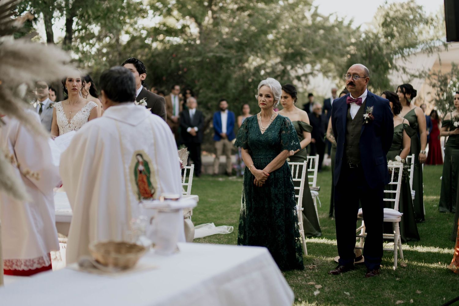 Outdoor wedding ceremony setup with white chairs and natural greenery in the background.