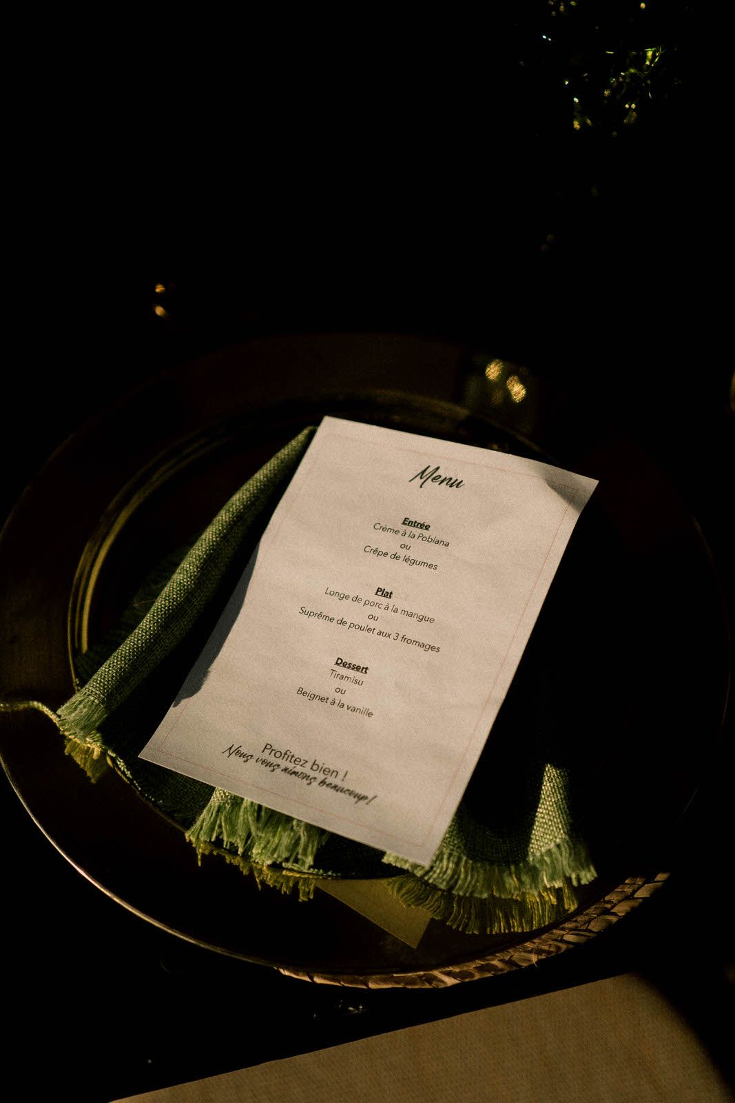 Wedding menu card placed on a dark plate with decorative green garnish.