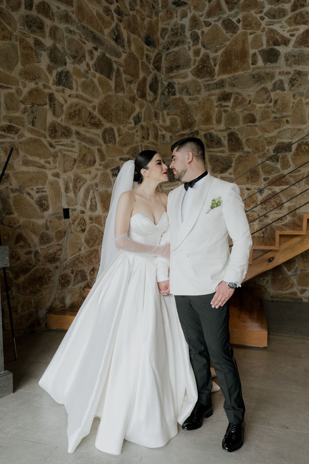 Romantic moment shared against a rustic stone wall backdrop.