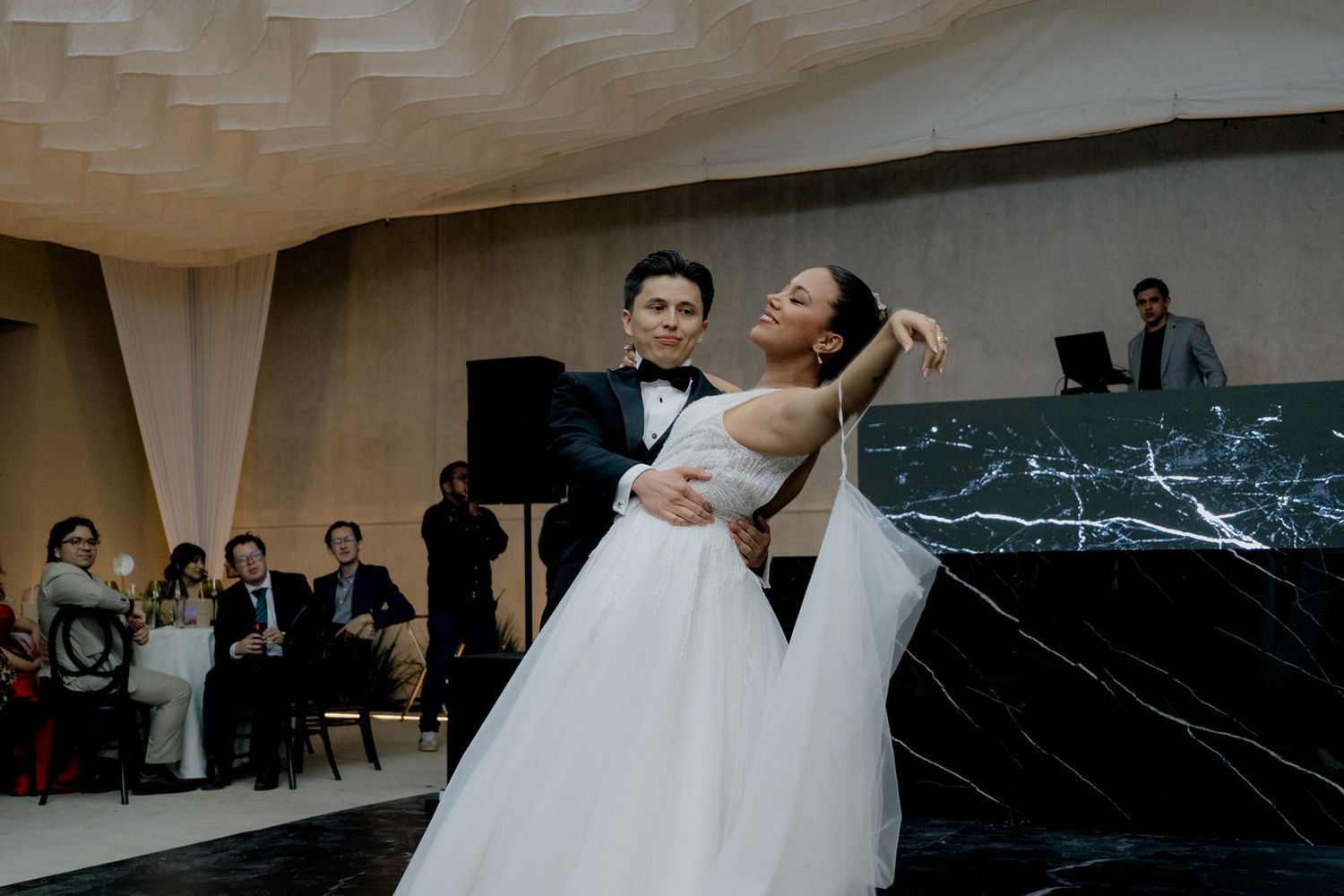 Bride and groom share their first dance at an elegant wedding reception with marble decor.