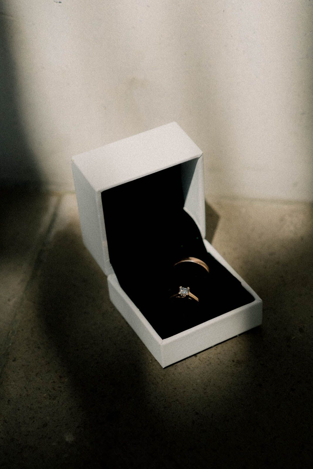 Diamond engagement ring displayed in a white jewelry box with dramatic lighting.