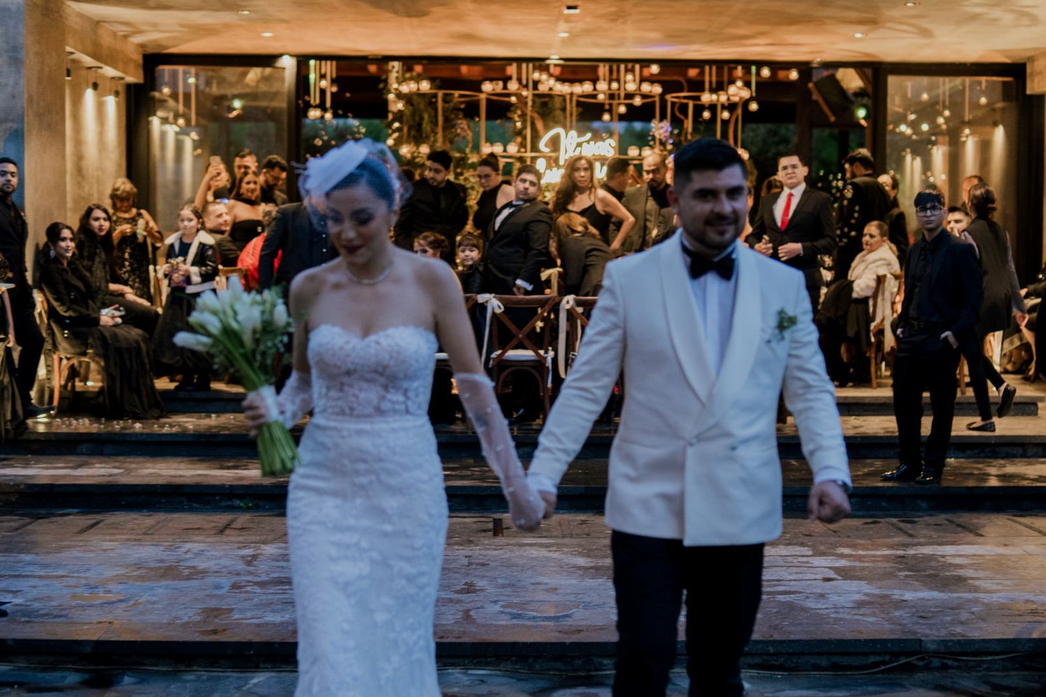 Elegant wedding celebration with guests dancing in a beautifully decorated indoor venue.