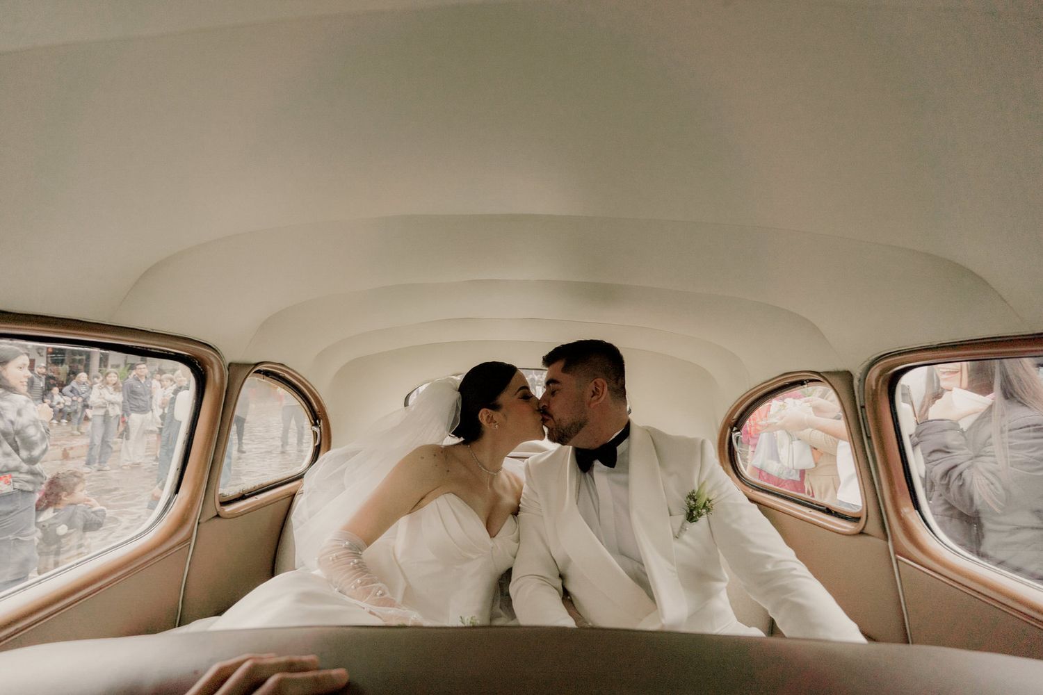 Intimate moment captured inside classic car with couple in wedding attire.