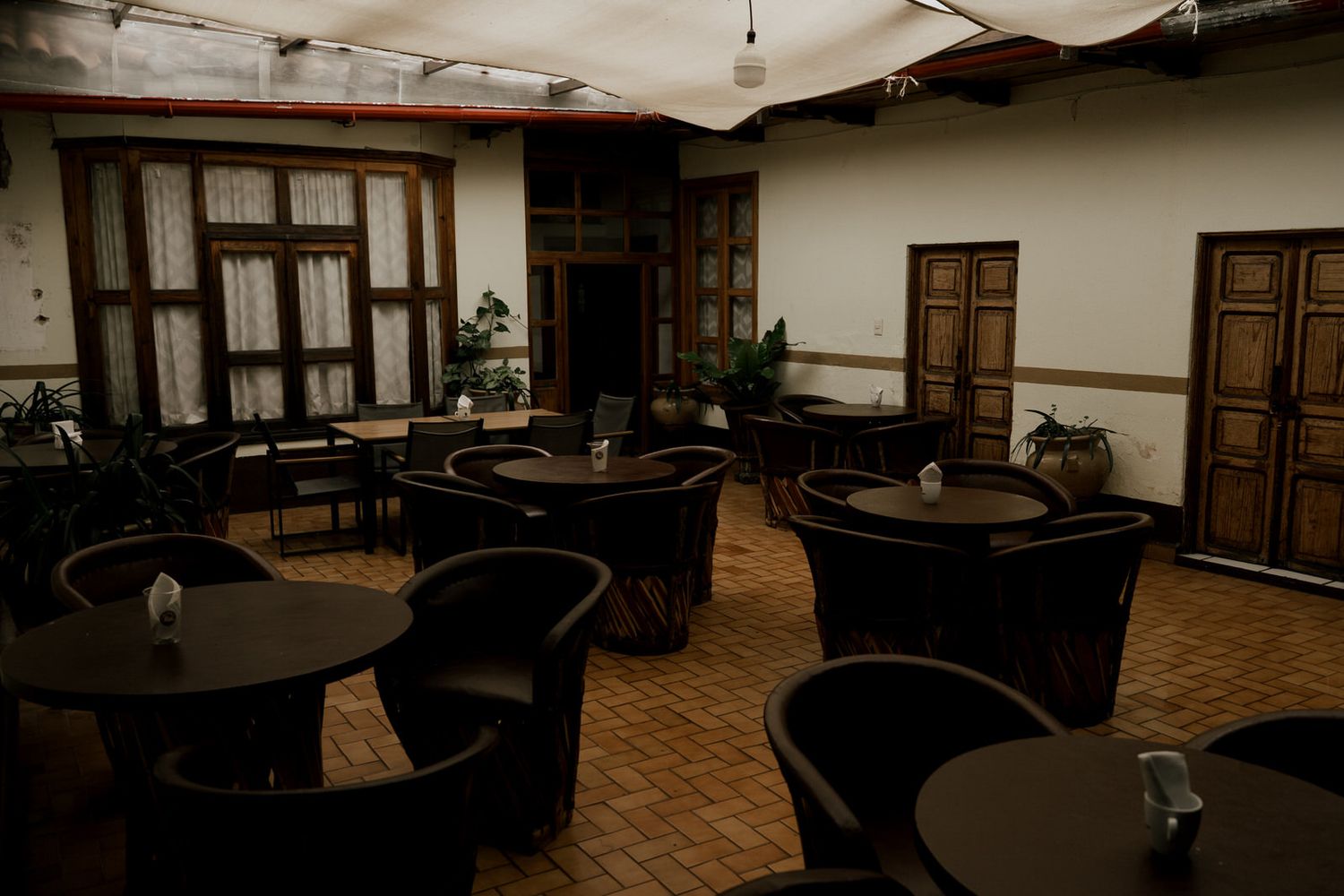Dark wooden furniture arranged in a spacious room with tiled floors and wooden doors.