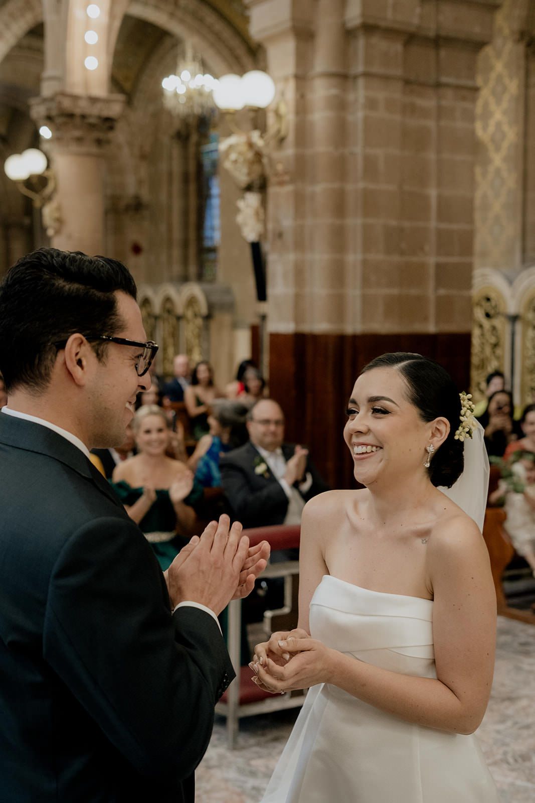 Bride and groom exchange rings at church altar, smiling joyfully during wedding ceremony.