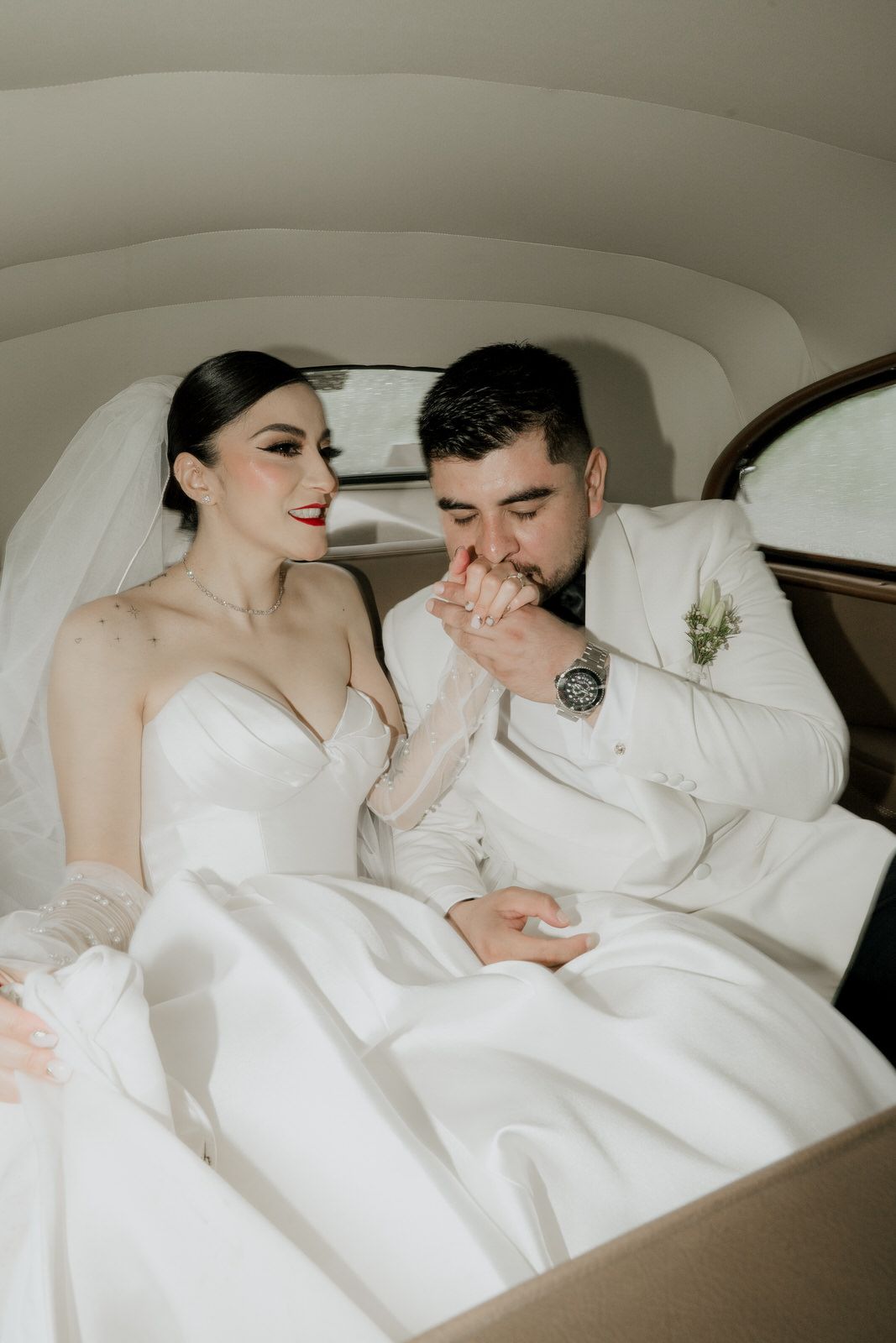Romantic wedding couple moment captured in the back of a classic car.