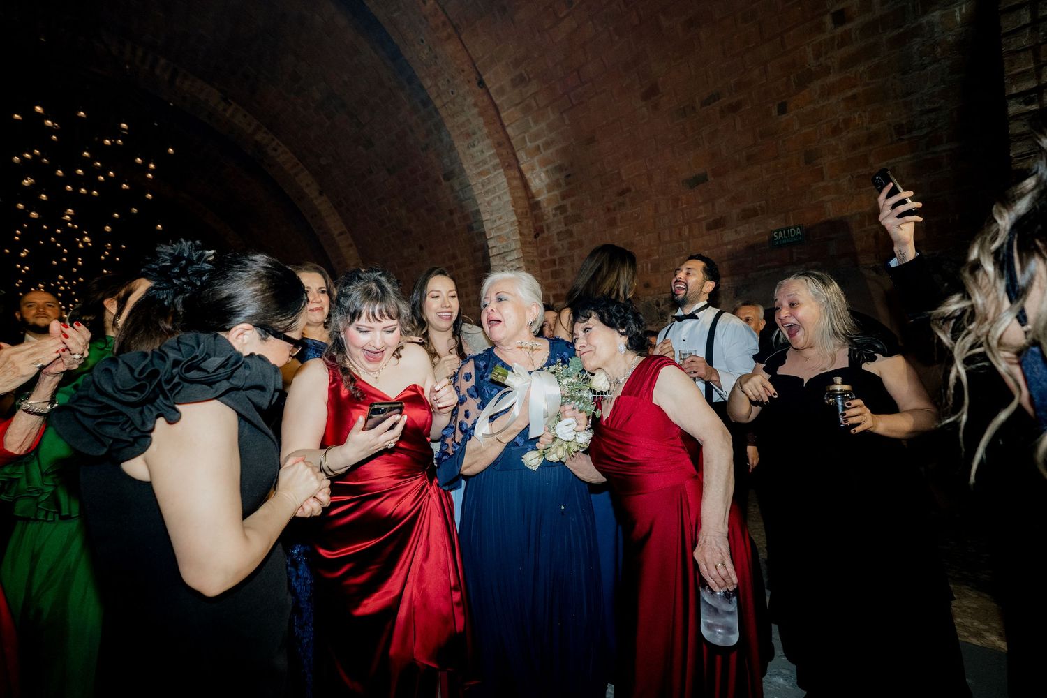 Wedding reception dance floor filled with guests celebrating under dim lighting and disco effects.