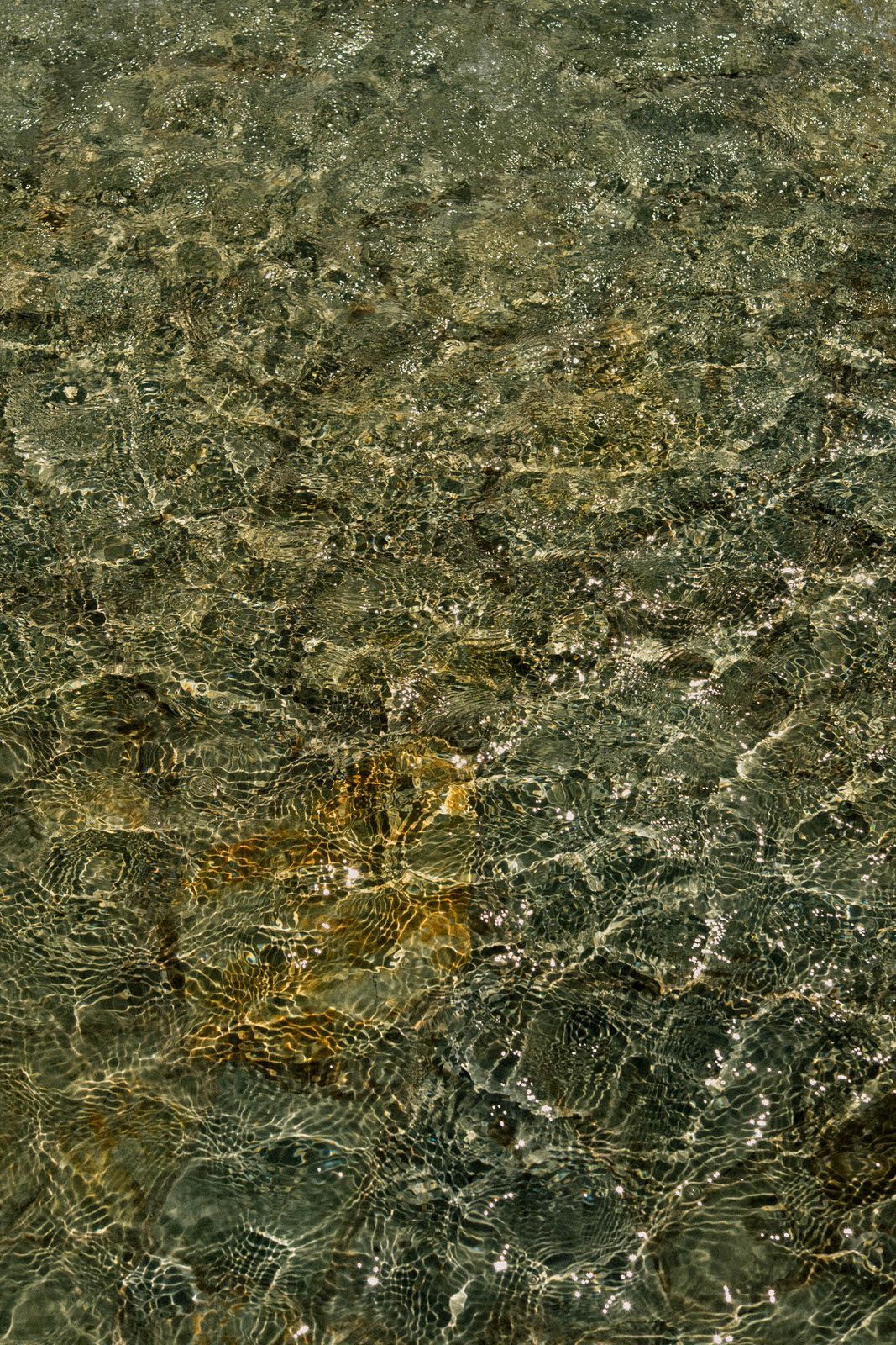 Abstract pattern of rippling water creating dark and light reflections on surface.