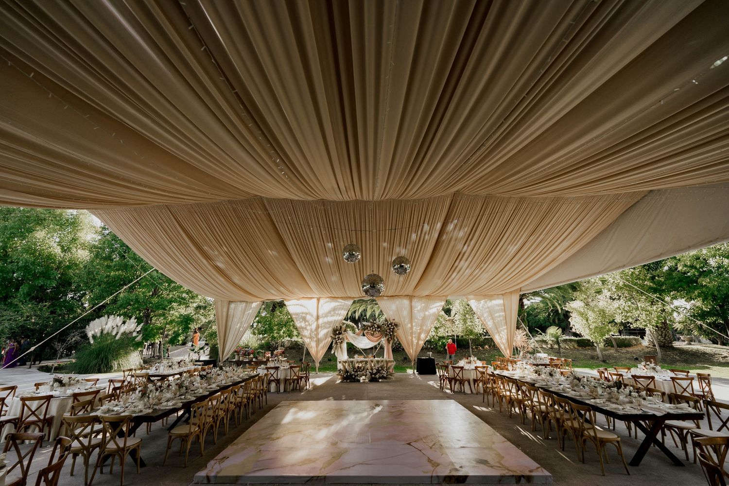 Dramatic tent ceiling draping creates an elegant canopy over wedding reception tables and chairs.