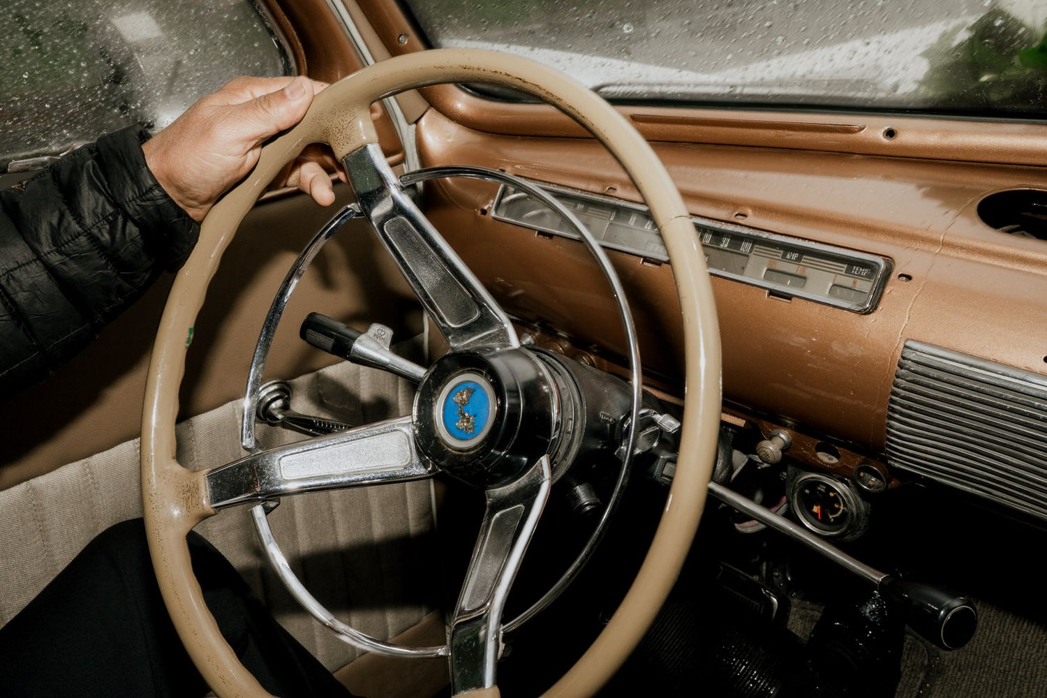 Vintage car dashboard and steering wheel with retro brown interior details.