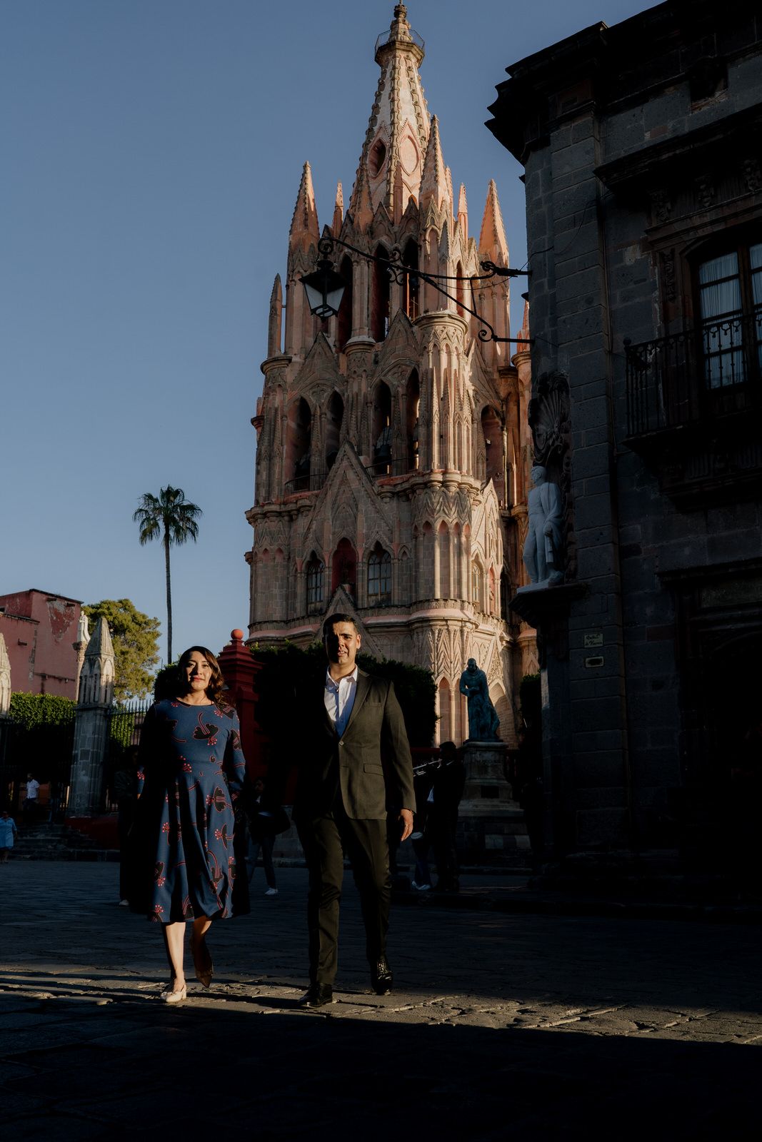Silhouettes of a couple stand in front of a majestic Gothic cathedral during golden hour.