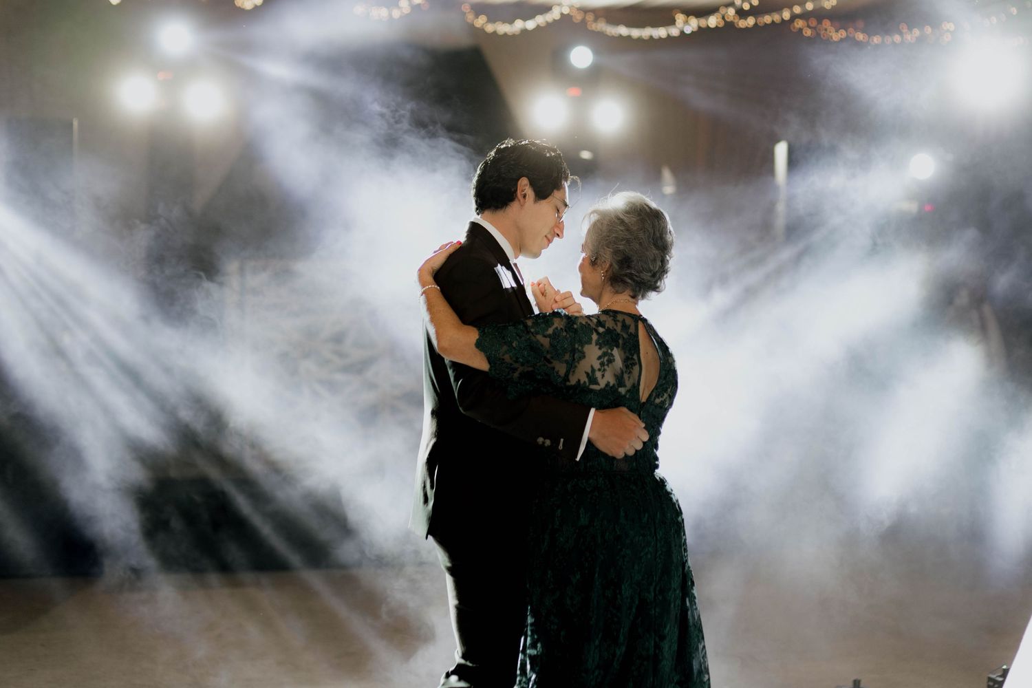 A wedding dance floor illuminated by string lights and a disco ball creates a magical atmosphere.