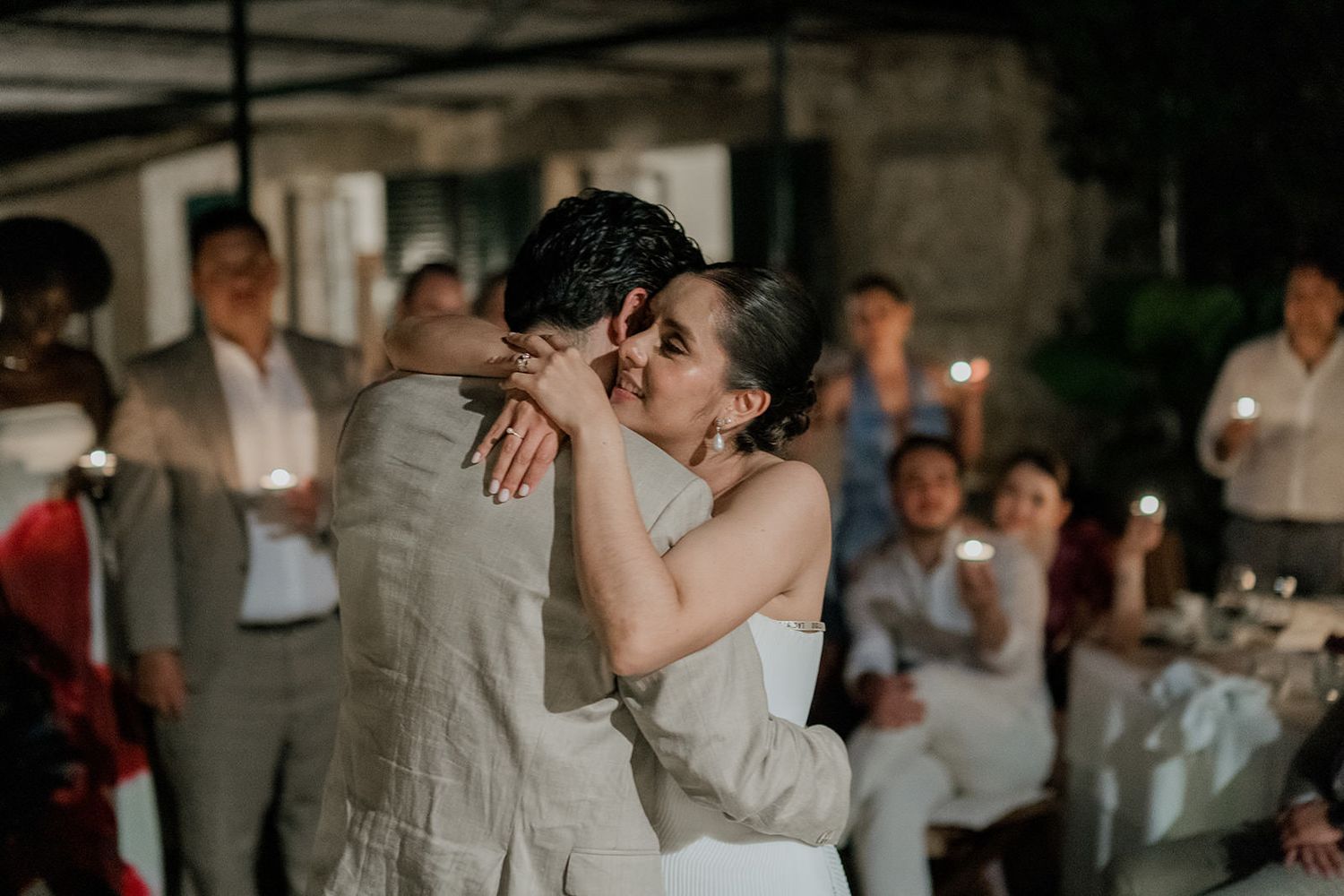 Newlyweds share an intimate dance moment at their wedding reception as guests look on in the background.