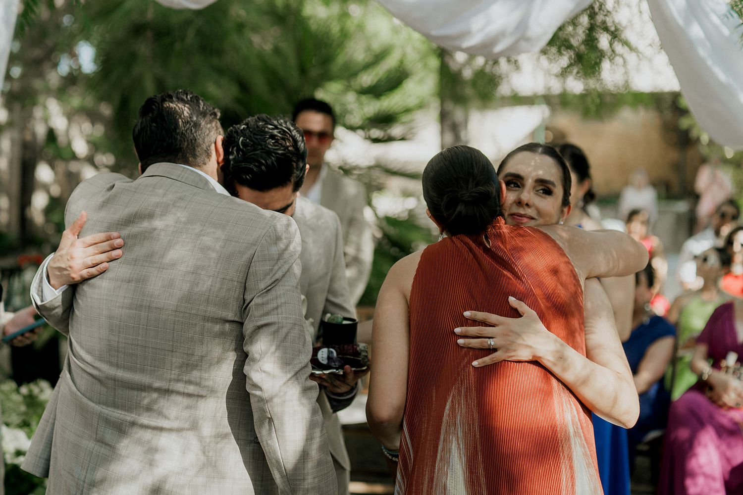 Outdoor wedding celebration with white draped fabric and natural greenery in the background.