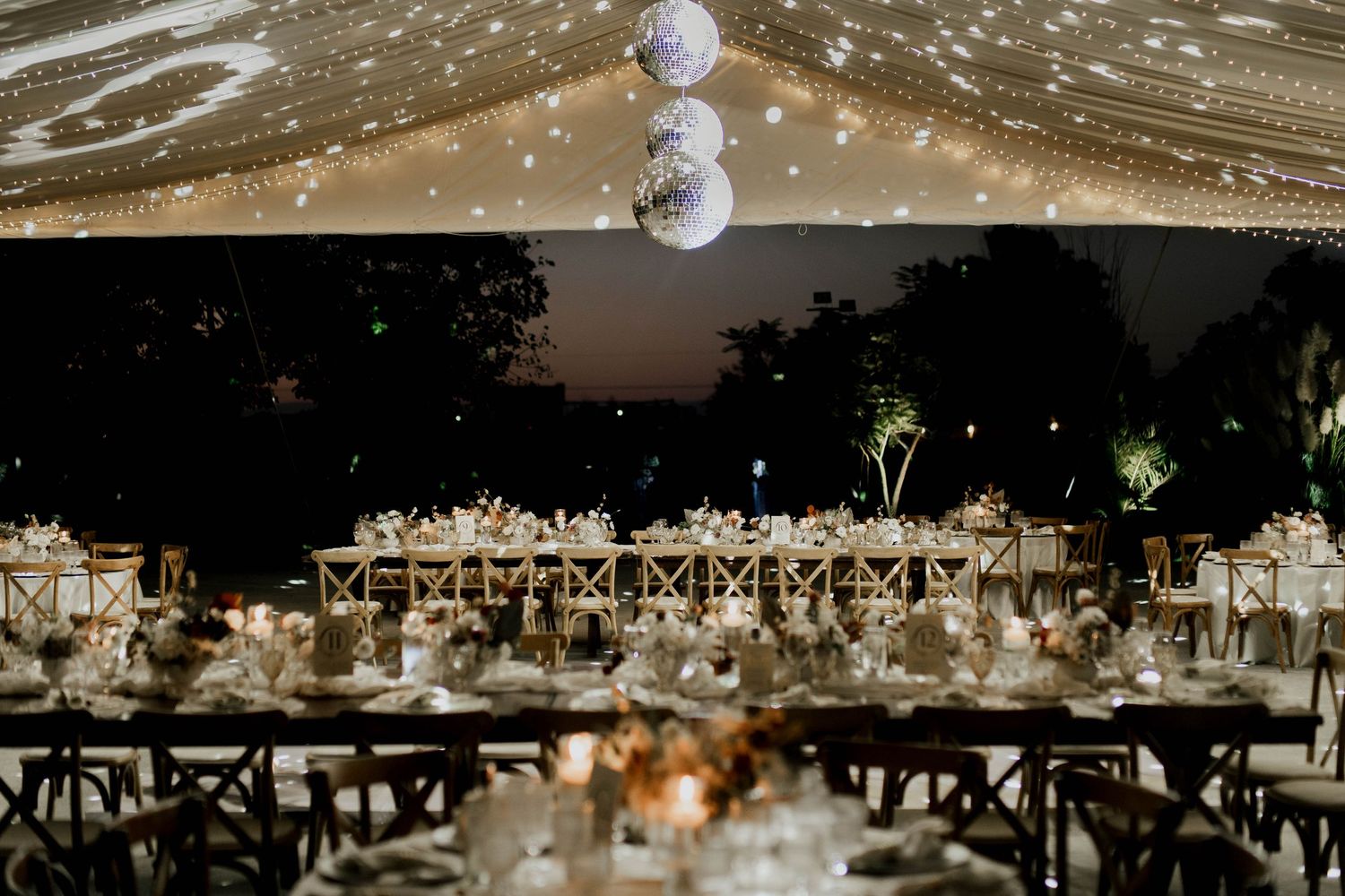 Wedding reception space with disco balls and string lights creating a magical atmosphere.