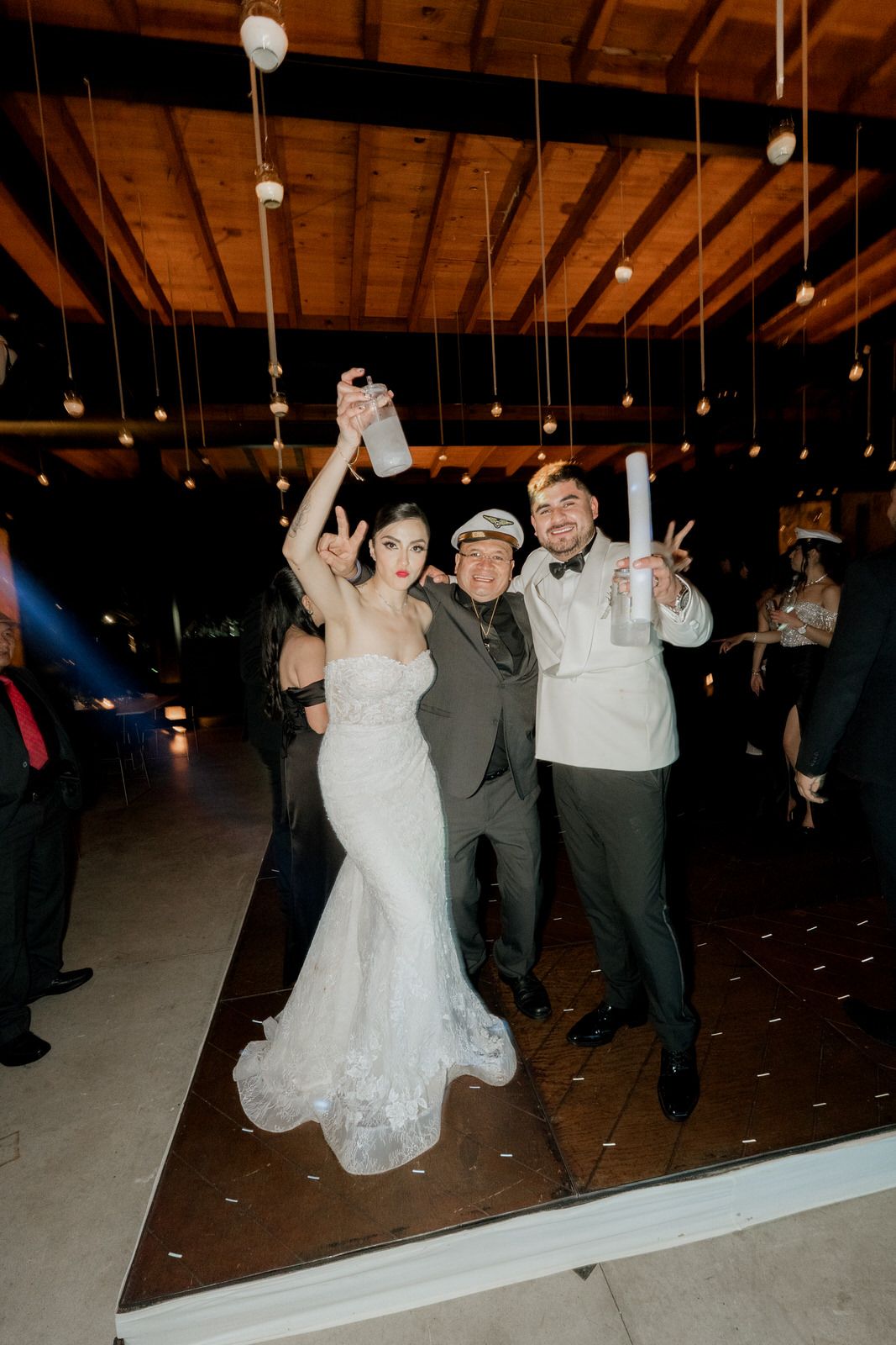 Wedding celebration with guests dancing enthusiastically on wooden floor.