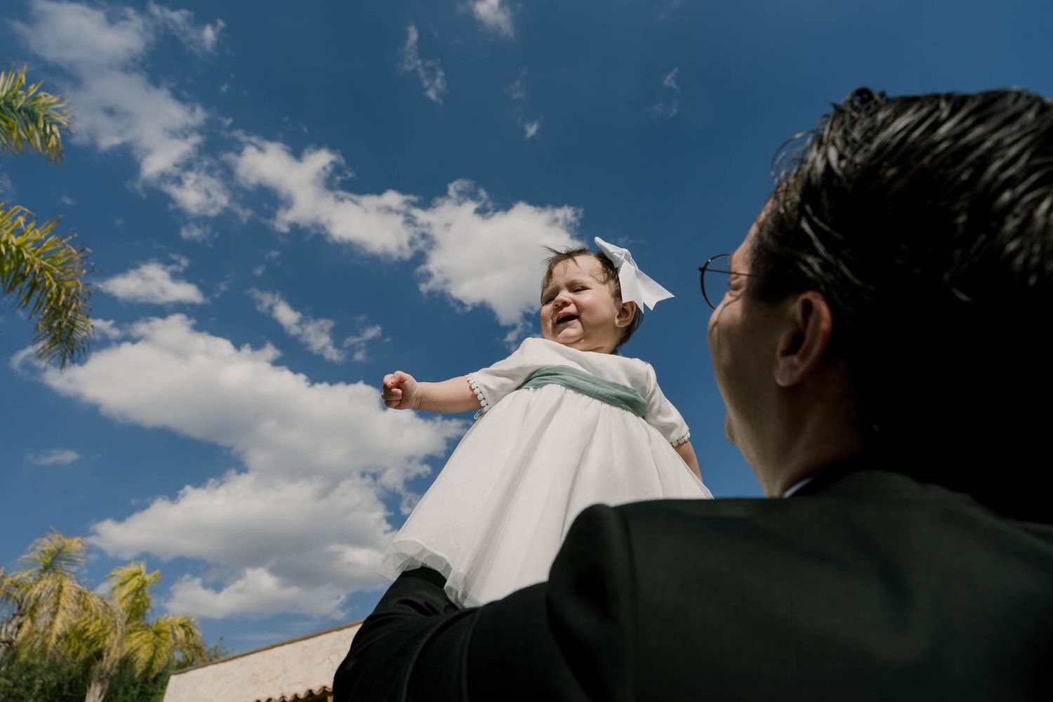 A joyful moment captured against blue skies during an outdoor wedding celebration.