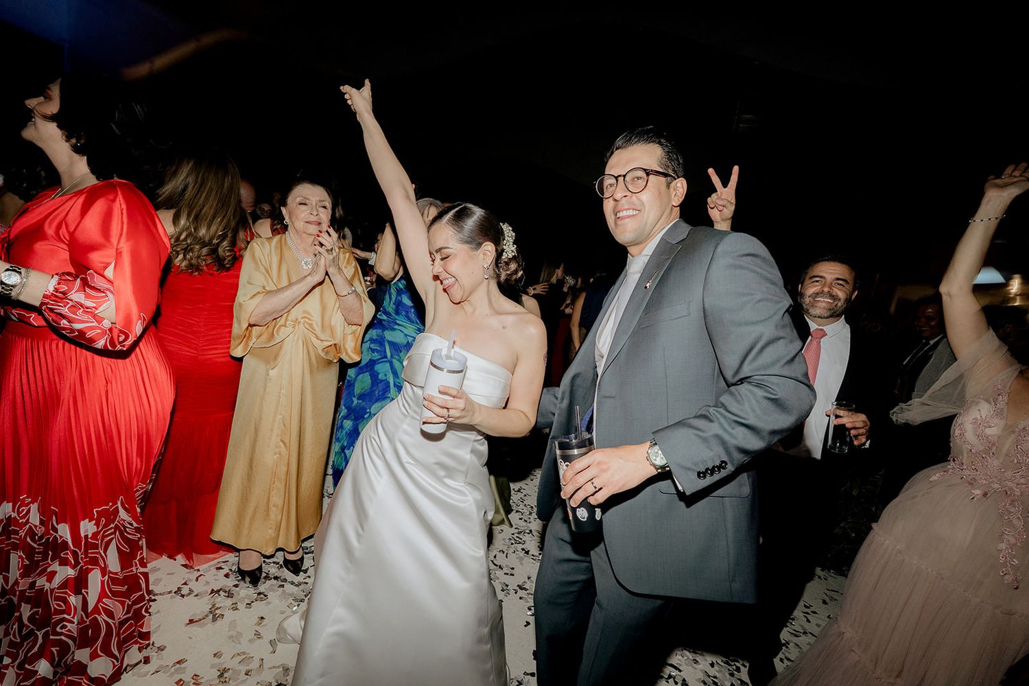 Bride and groom dancing joyfully with guests at a lively wedding reception party.