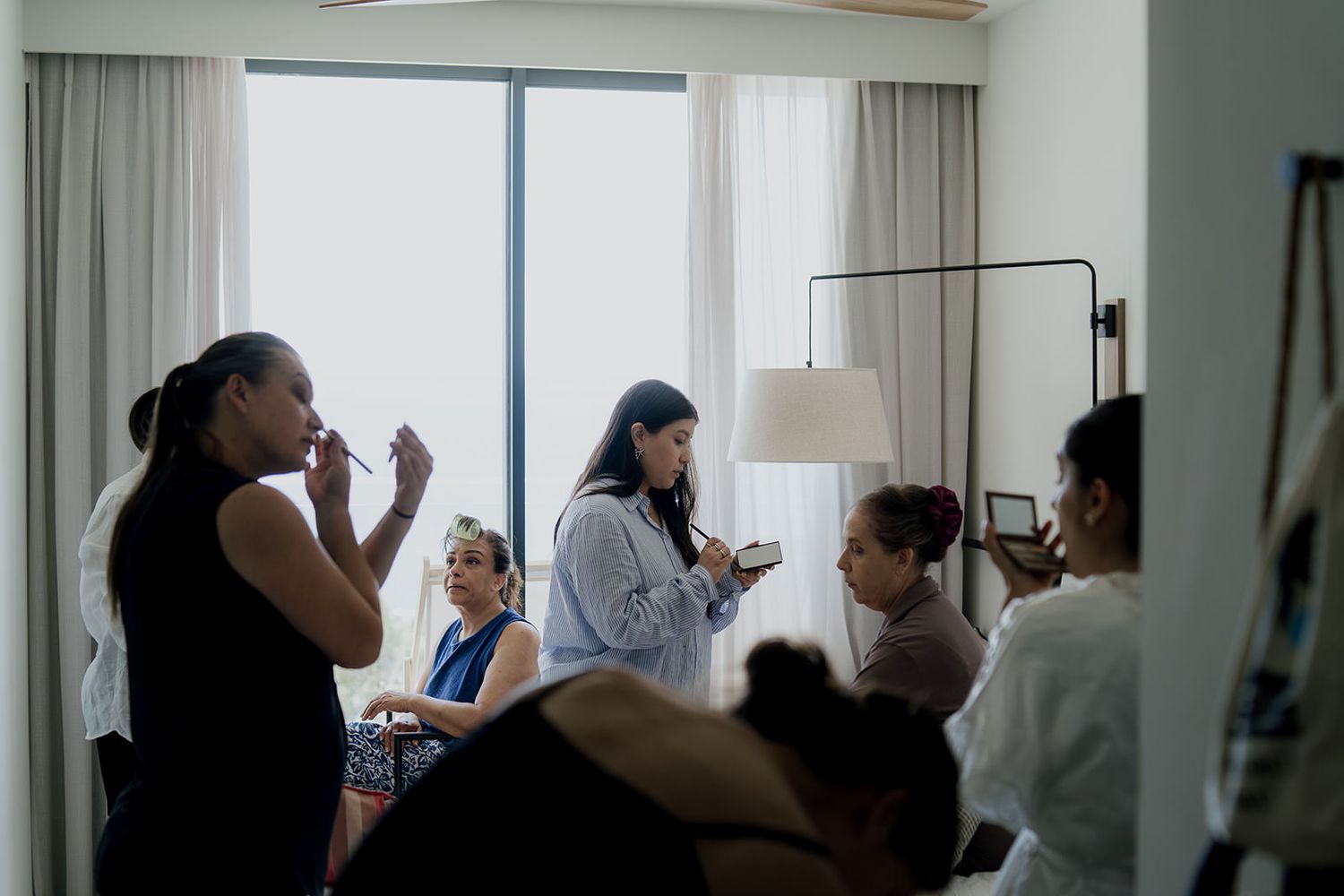 People gathered in a bright room with white curtains and natural lighting.