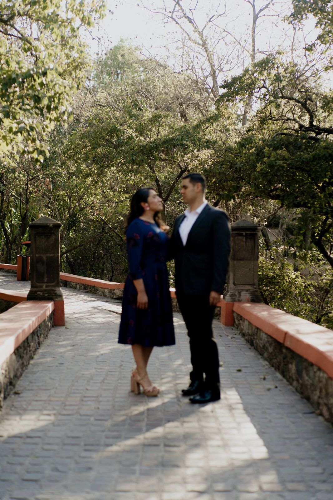 Couple sharing a romantic moment on a stone pathway surrounded by greenery.