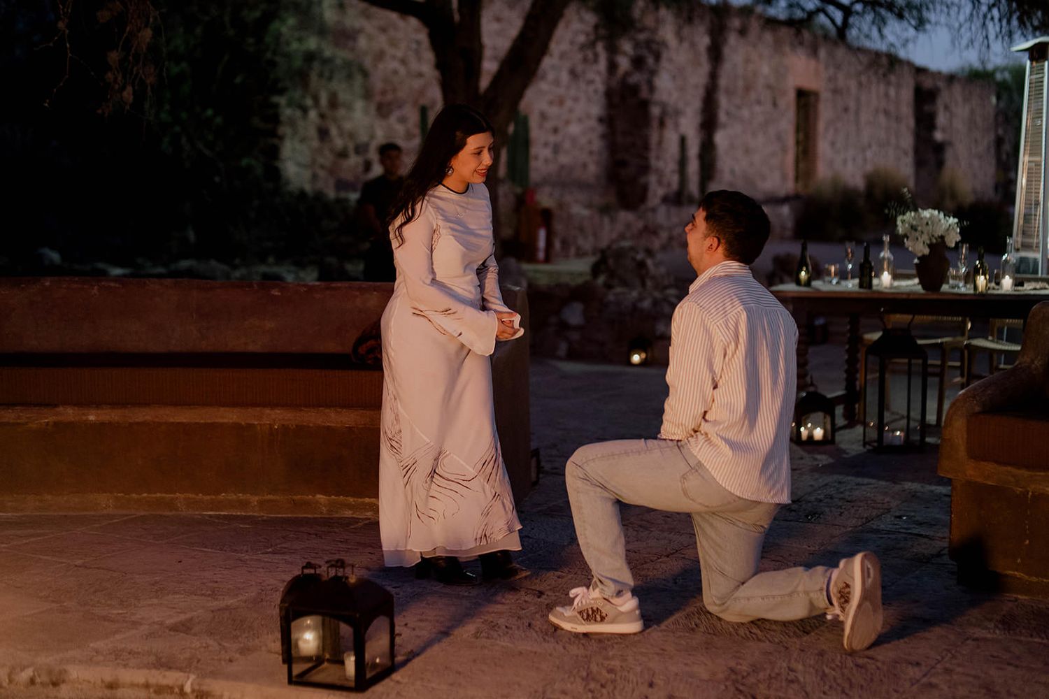 A special moment unfolds between two people near lanterns at twilight.