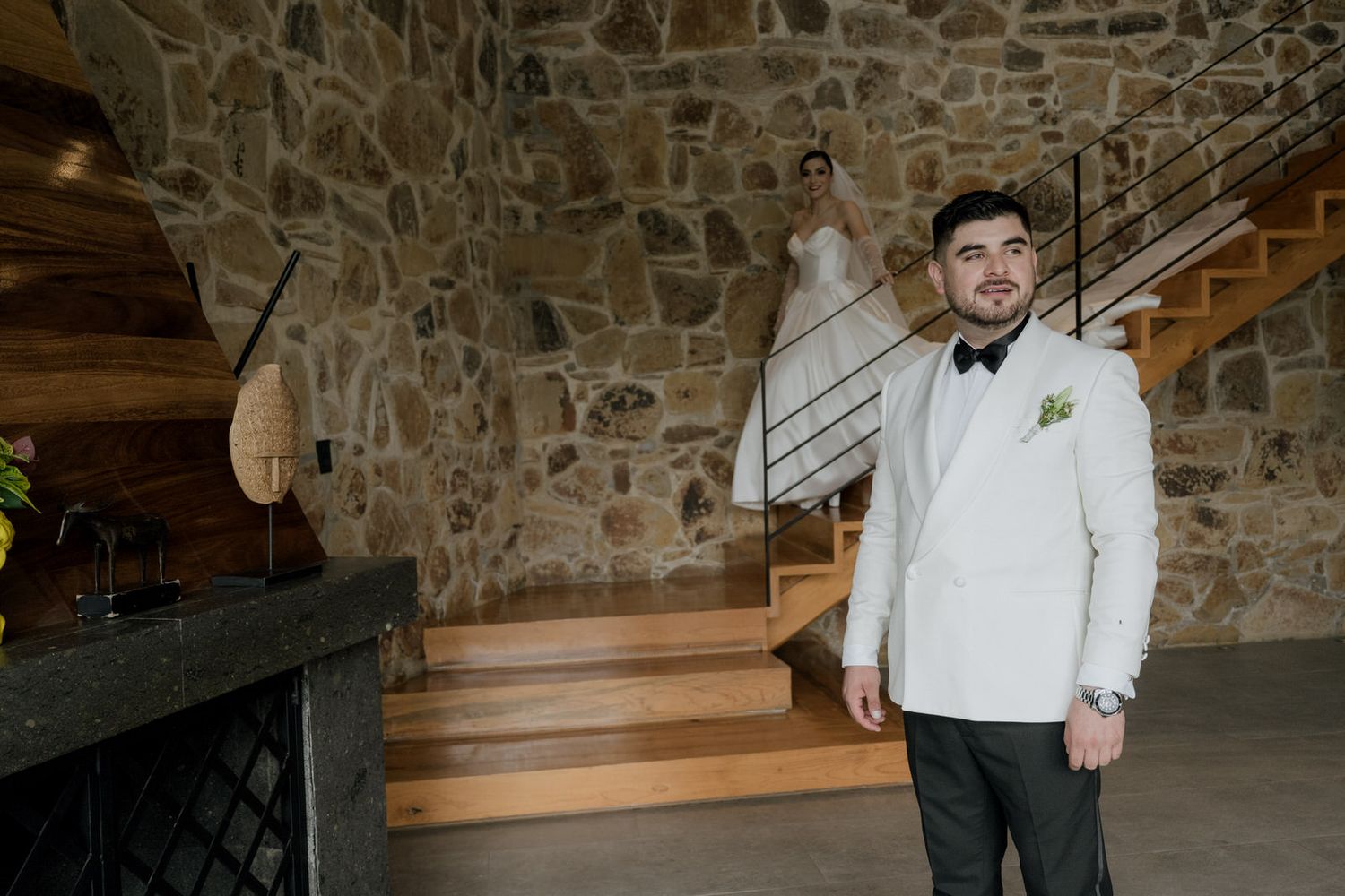 Elegant wedding venue interior with stone walls and wooden staircase.